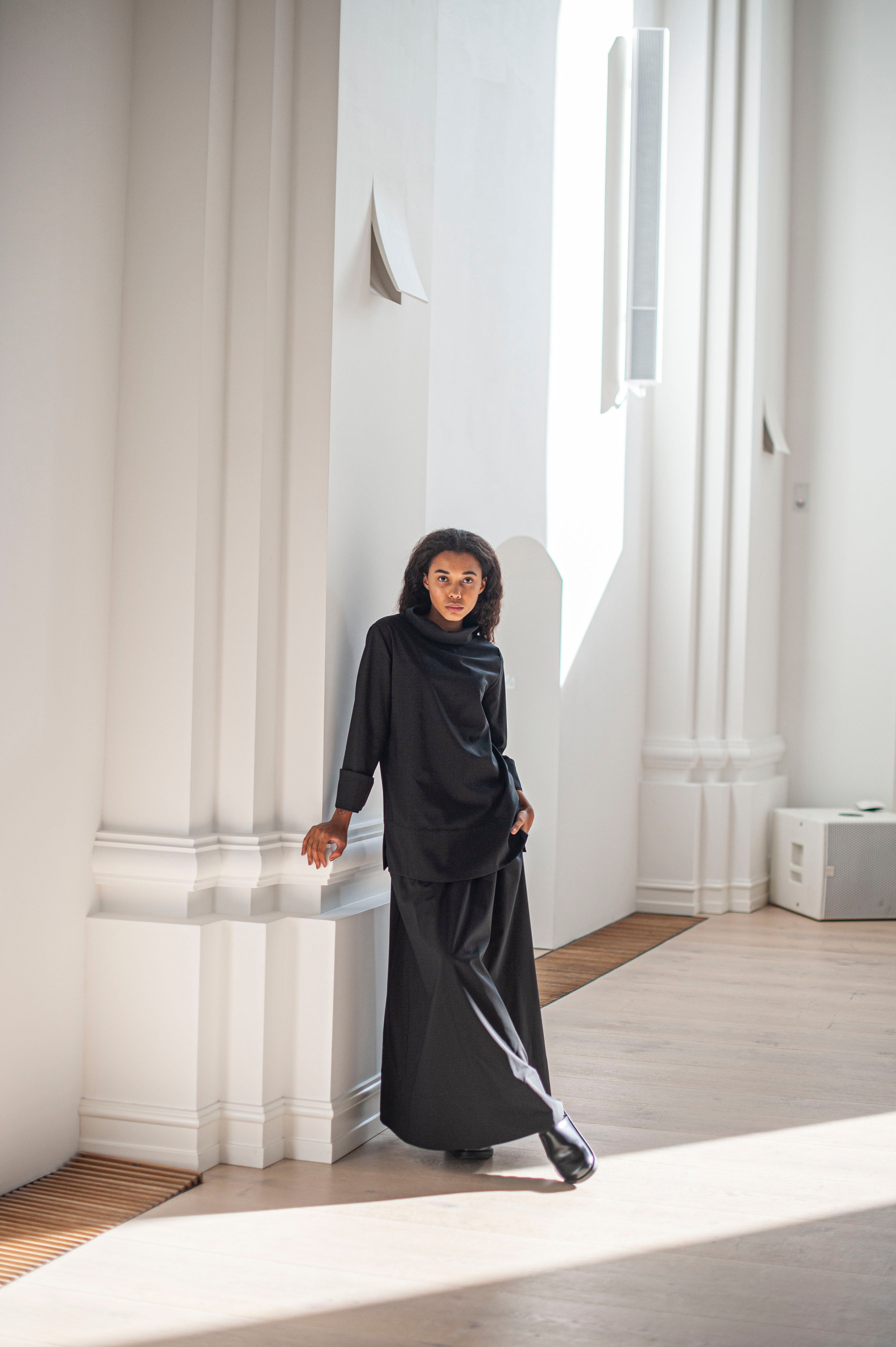 Elegant black wool top with a high neckline and foldback sleeve cuffs. Paired with a matching black A-line skirt.