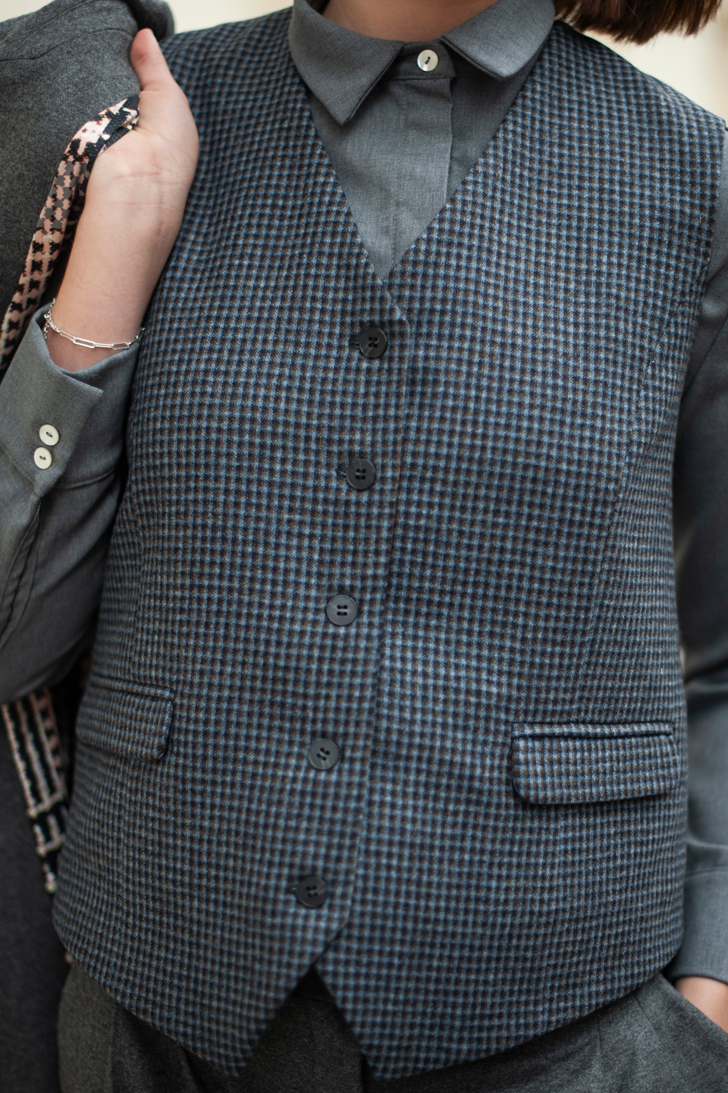 Women's blue checked classic waistcoat under a gray  merino wool shirt.