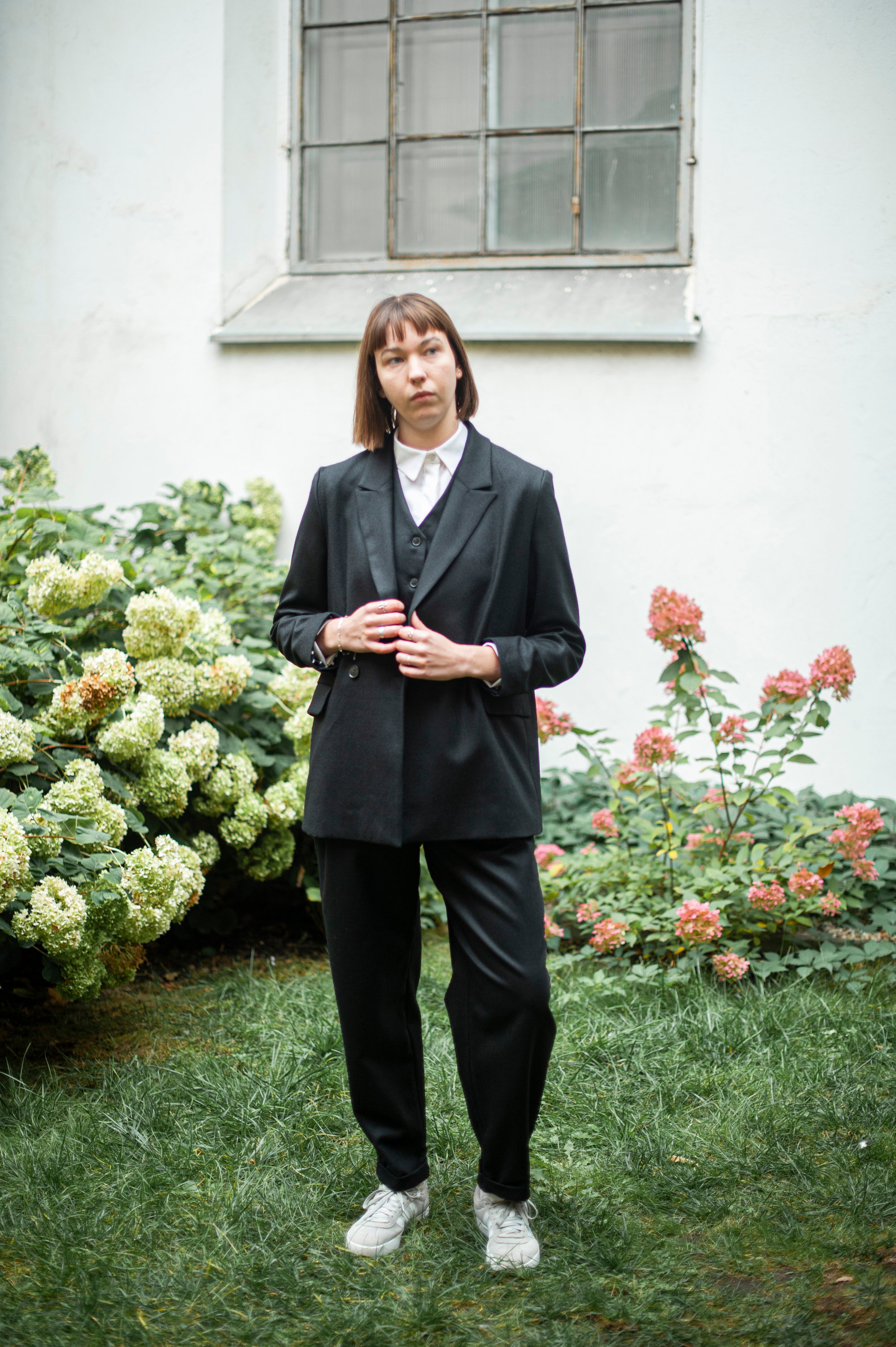 Black three-piece wool suit for women. The suit includes a double-breasted blazer, tapered leg pants, and a matching suit vest.