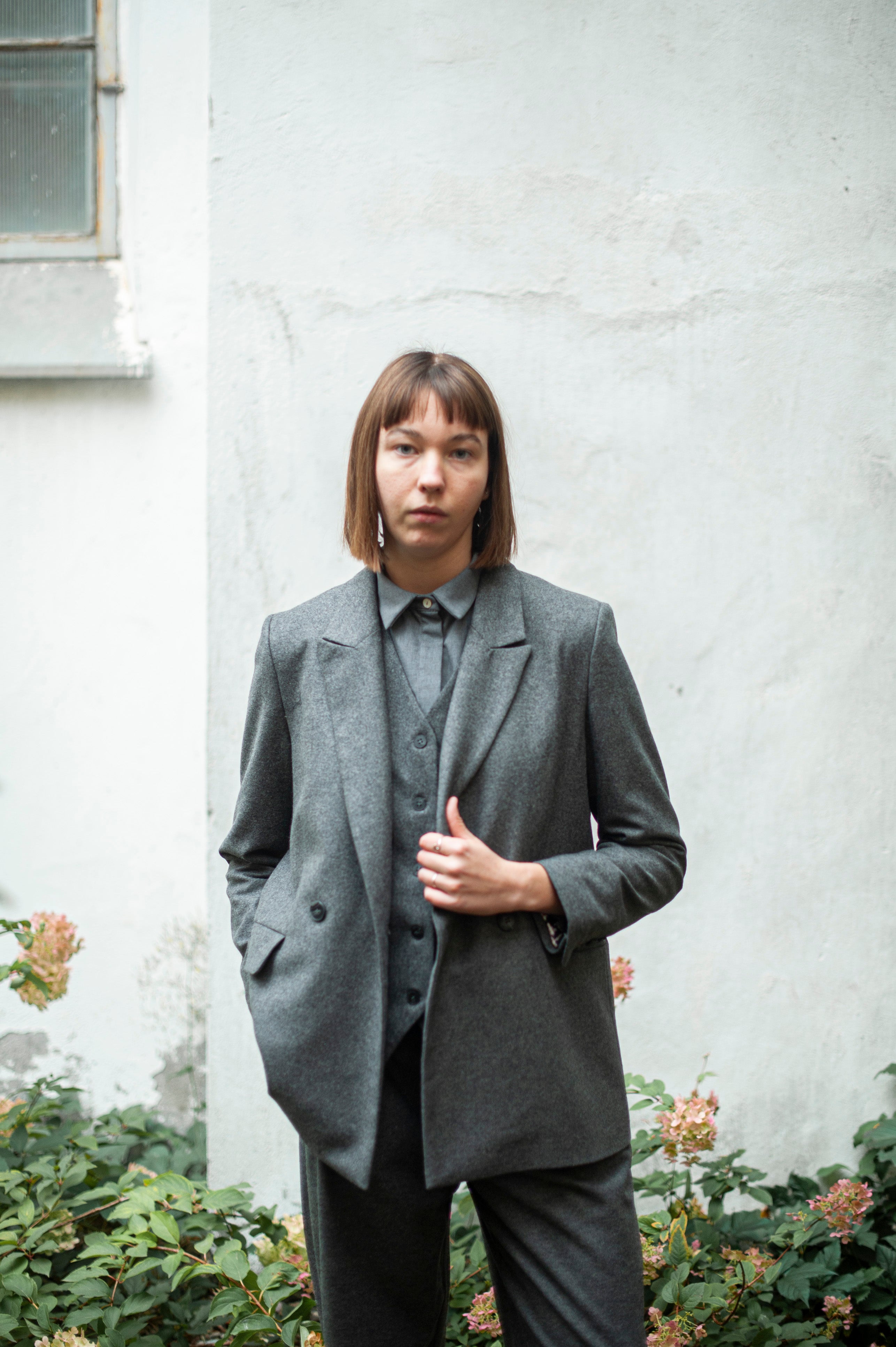 Grey double-breasted blazer, gray vest, and grey tapered leg pants with front pleats.