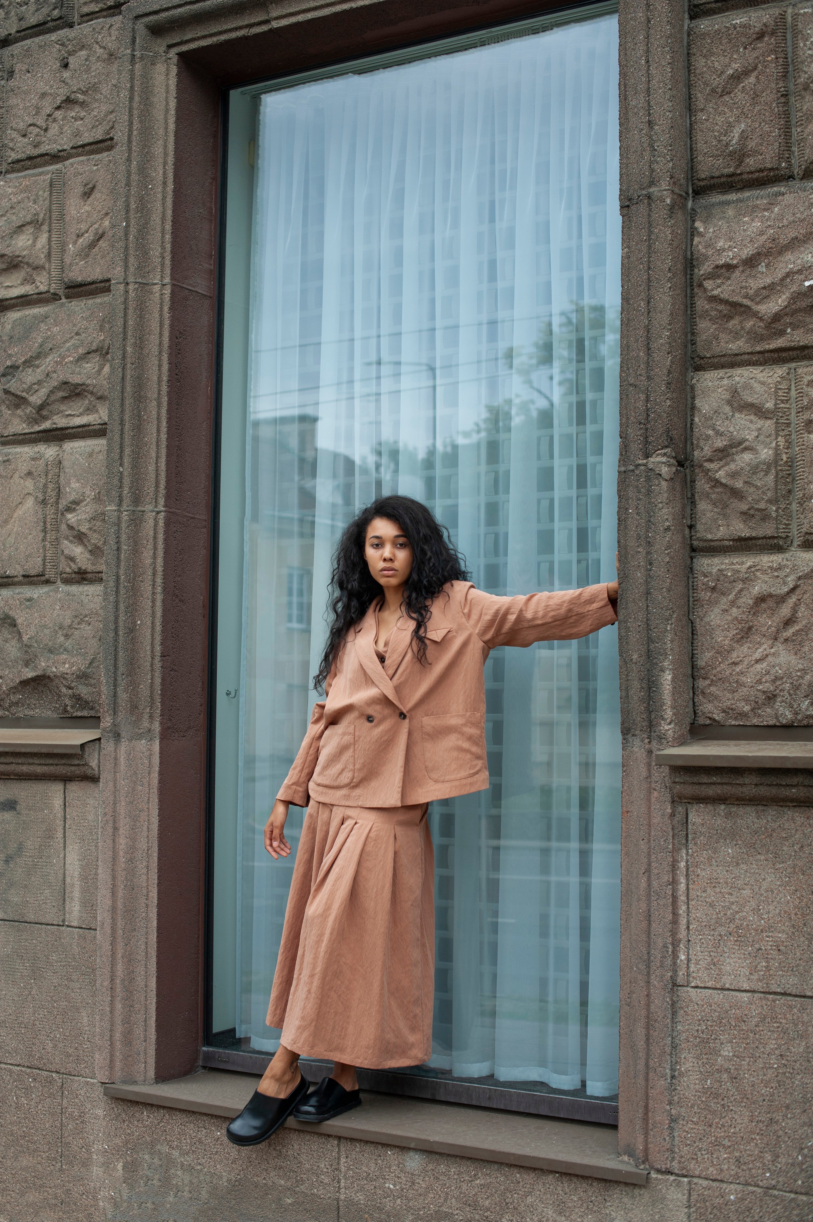 Light beige linen palazzo pants with chunky pleats. The pants are topped off with a matching loose-fitting blazer.