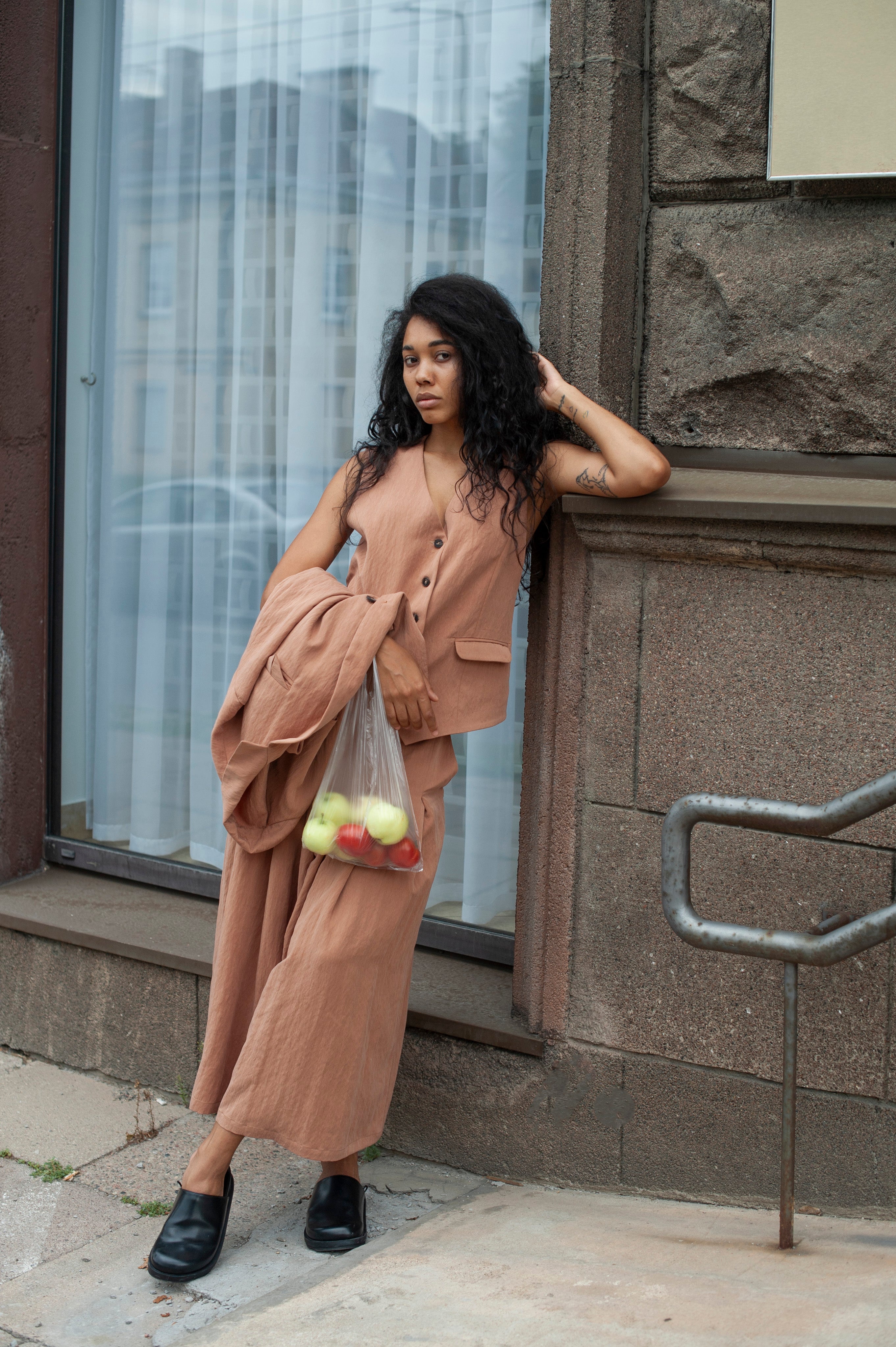 Women's linen vest with a button closured. The model is wearing a light beige color co-ord of a blazer, vest, and pleated pants