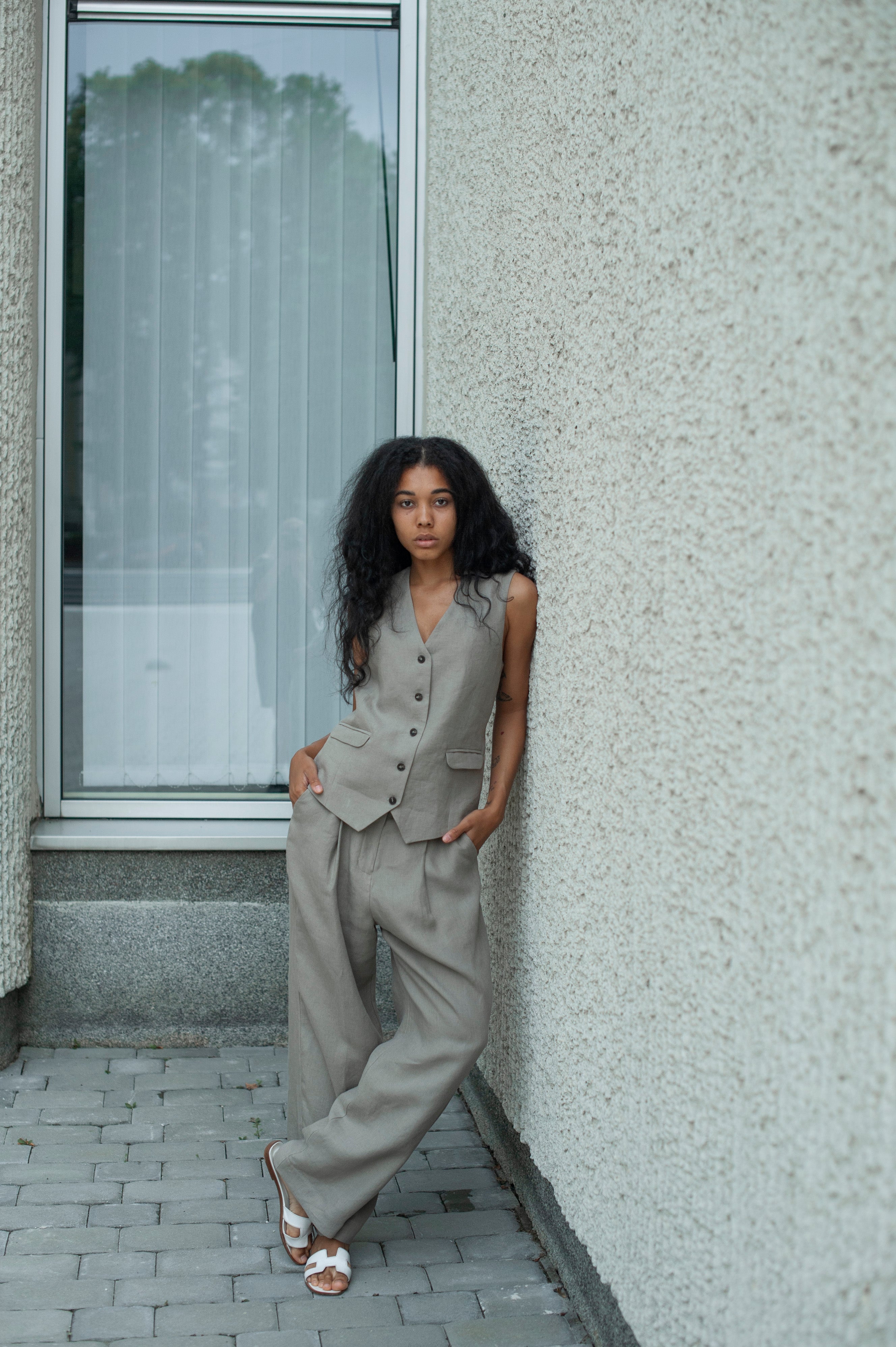 Light gray linen outfit of a linen vest and flowy pleated linen pants in a relaxed silhouette.