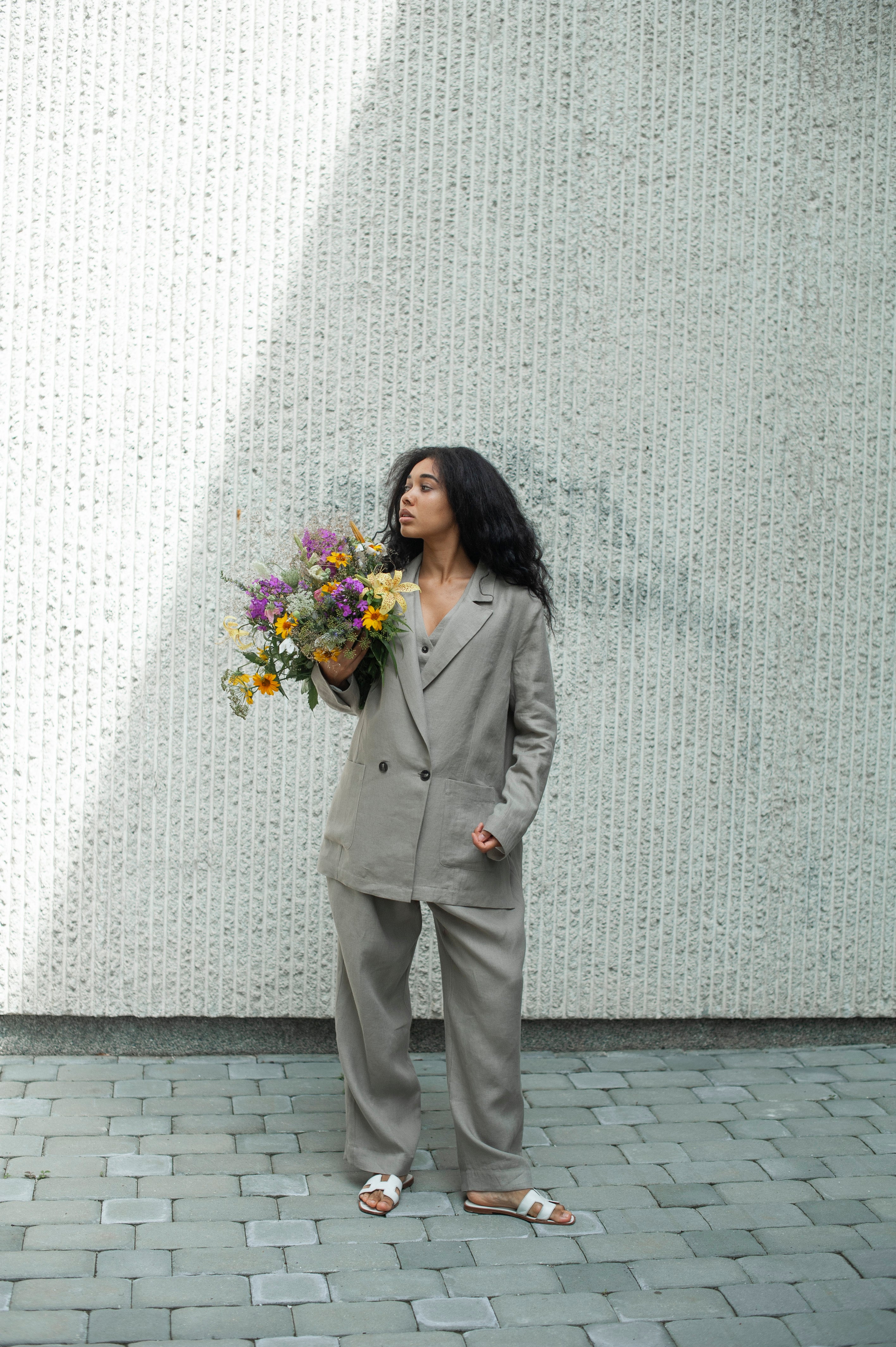A lady in a three-piece linen suit in grey. Linen blazer with a notched lapel collar.