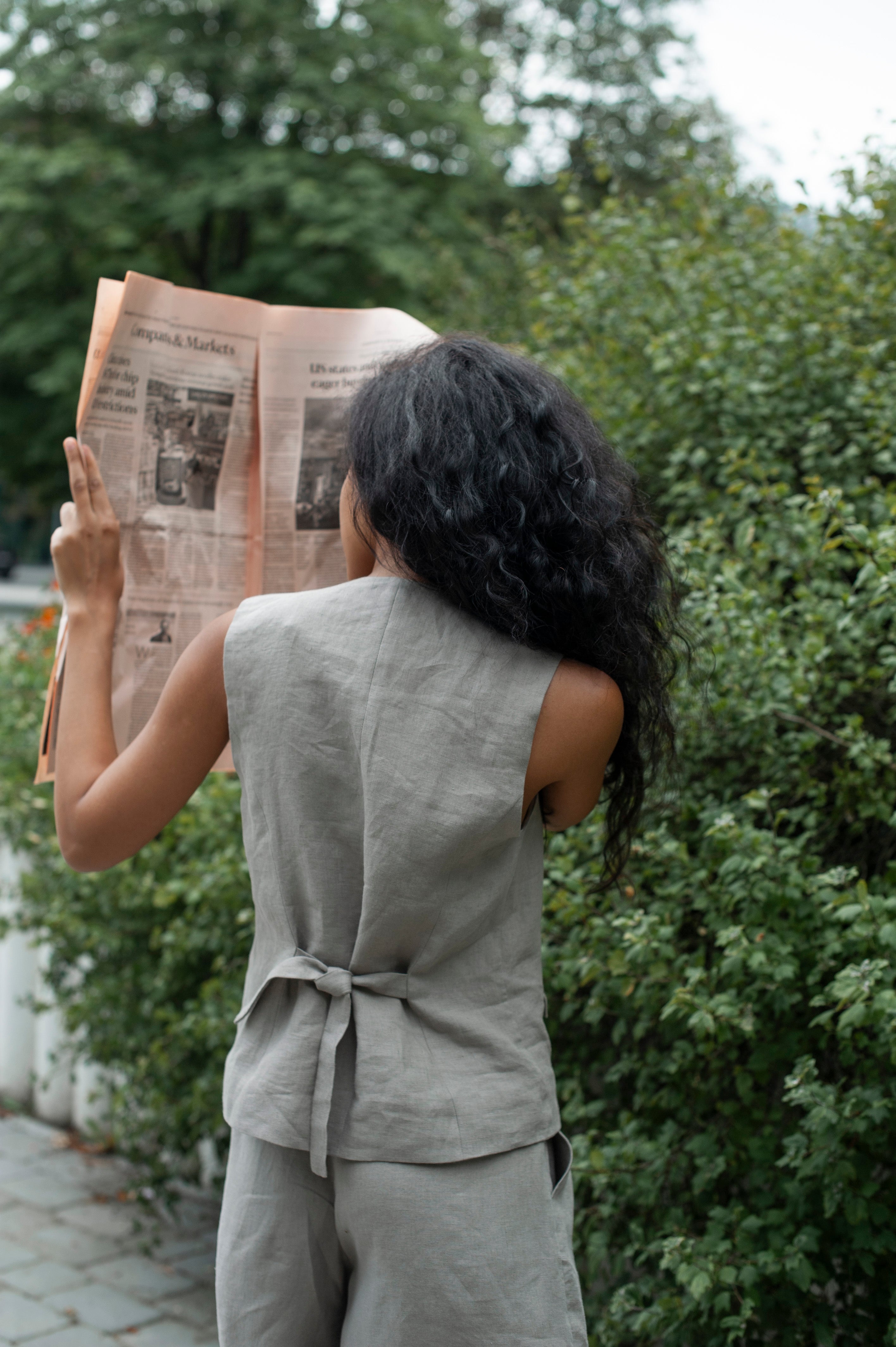 The back of a linen waist. The back boats two waist ties that help regulate the waist size of the vest.