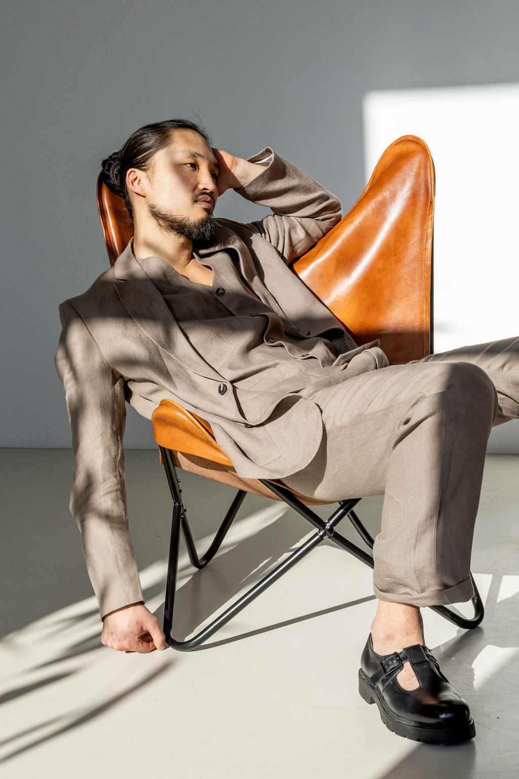 A man in a three-piece linen suit on a lounge chair