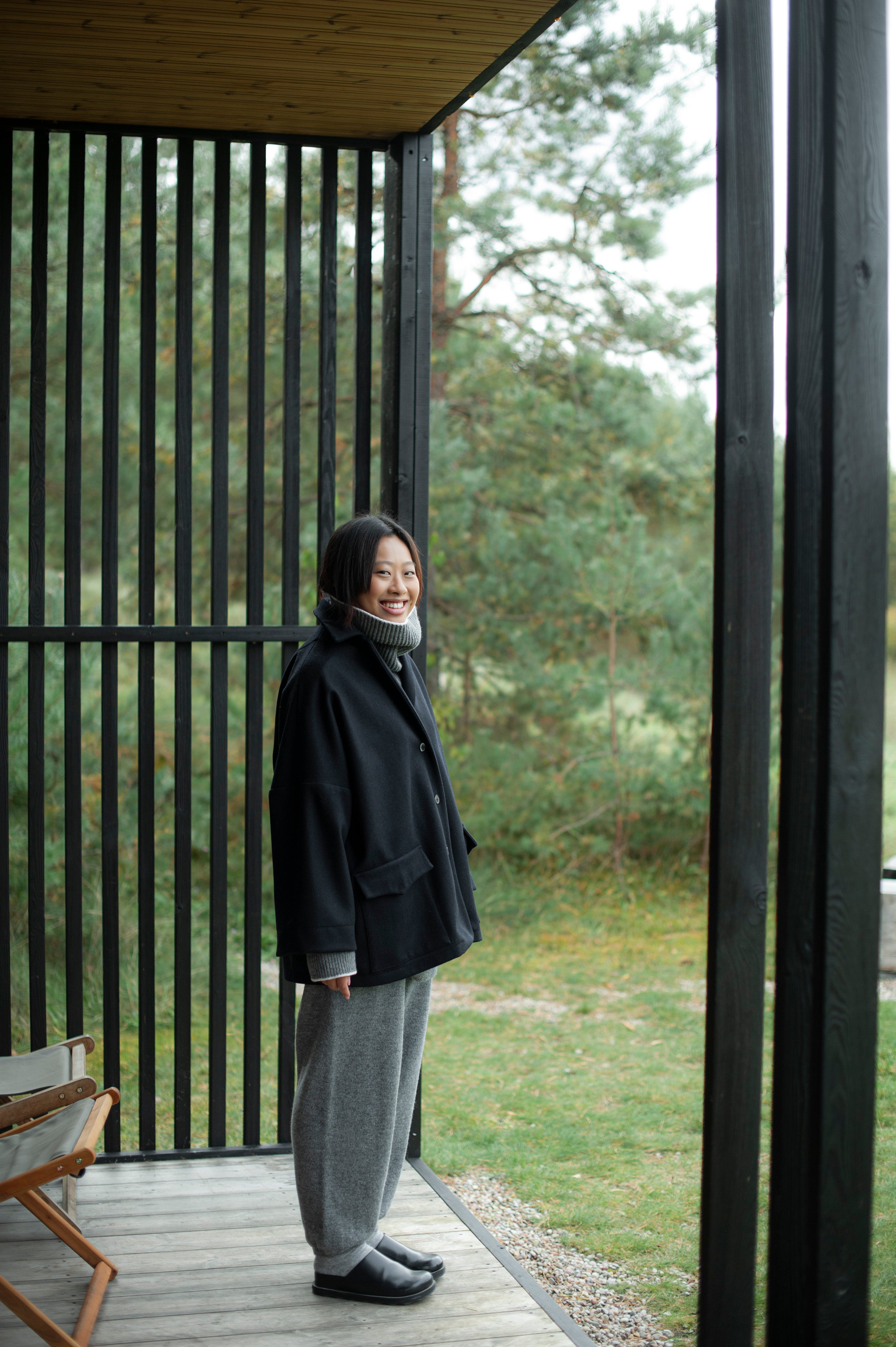 Women's dense boiled wool jacket in a boxy oversized silhouette. The jacket comes in one size only and is pictured paired with a grey knit set of a high-neck jumper and wide pants.
