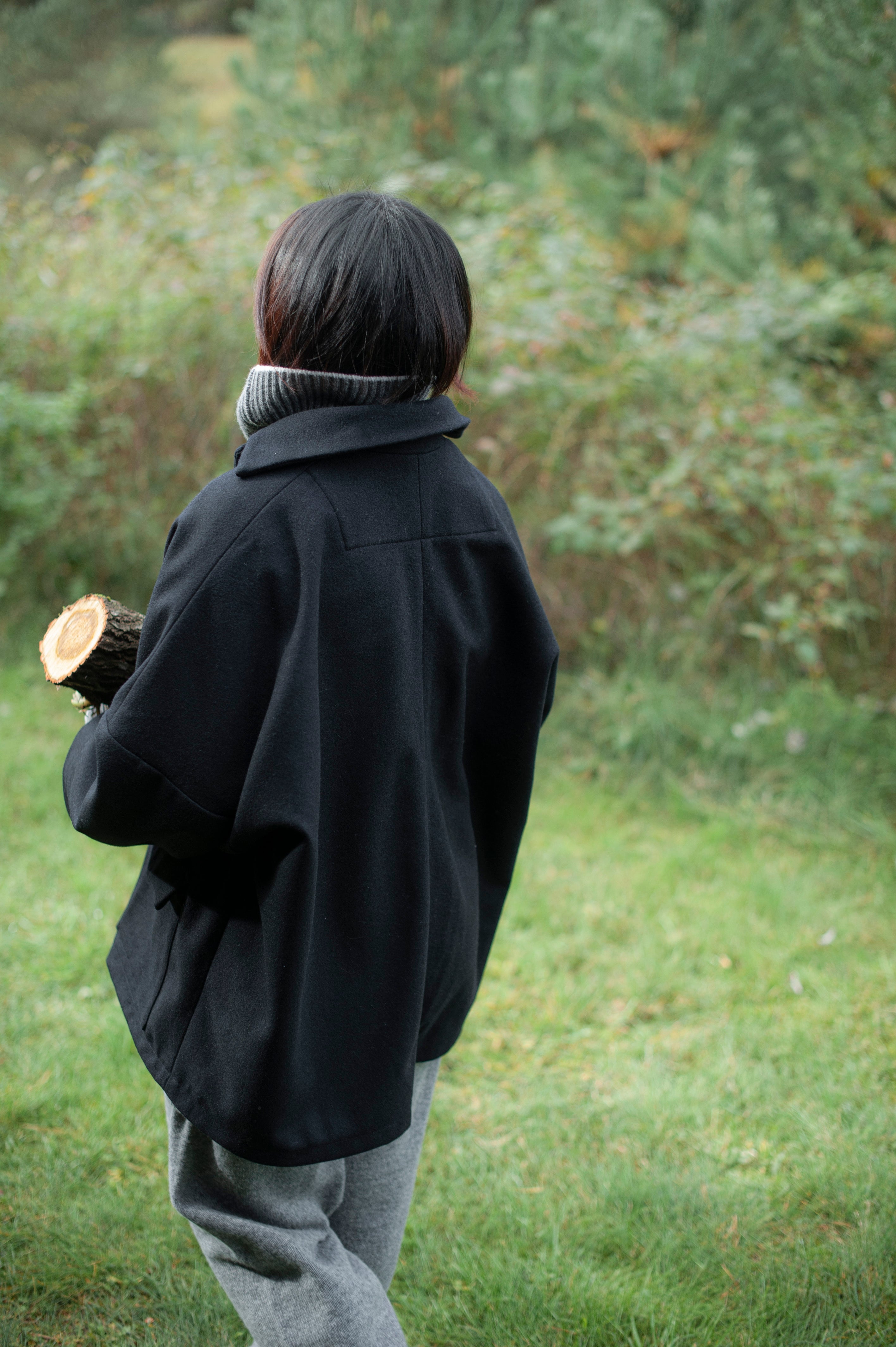 Women's dense boiled wool jacket in a boxy oversized silhouette. The jacket comes in one size only and is pictured paired with a grey knit set of a high-neck jumper and wide pants.