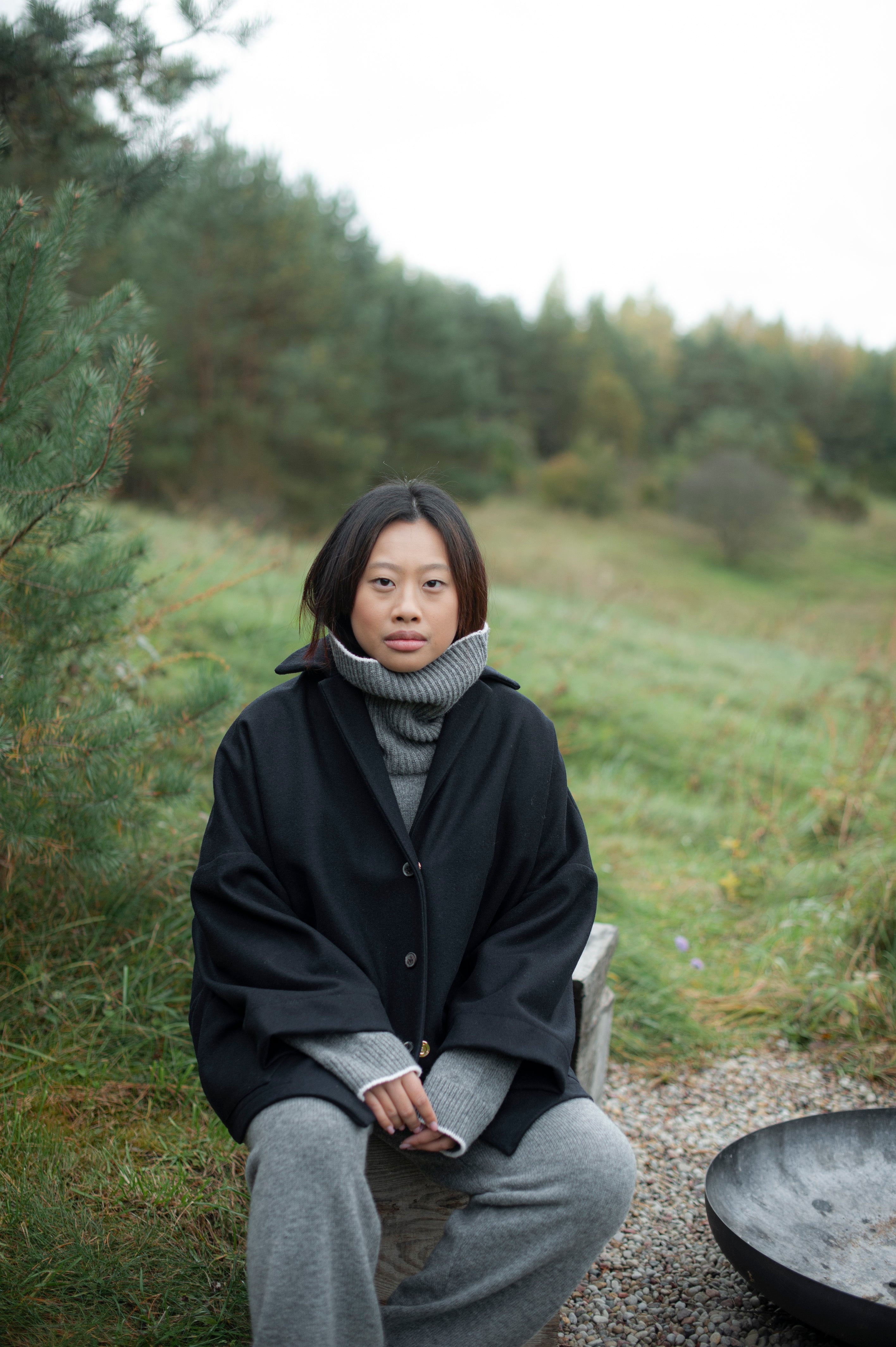 Women's dense boiled wool jacket in a boxy oversized silhouette. The jacket comes in one size only and is pictured paired with a grey knit set of a high-neck jumper and wide pants.