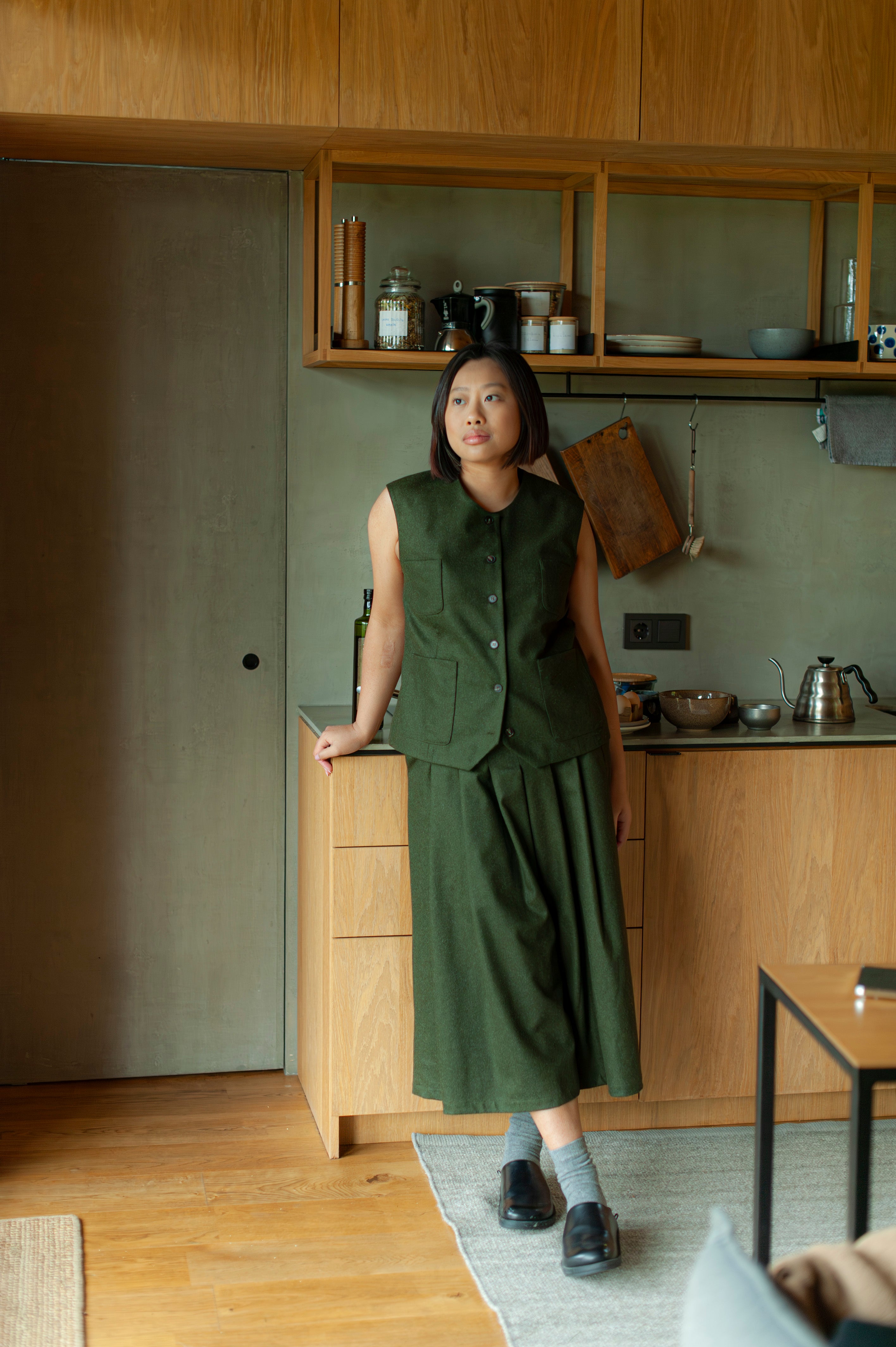 Green set of a wool button-up vest and pleated calf-length culottes.