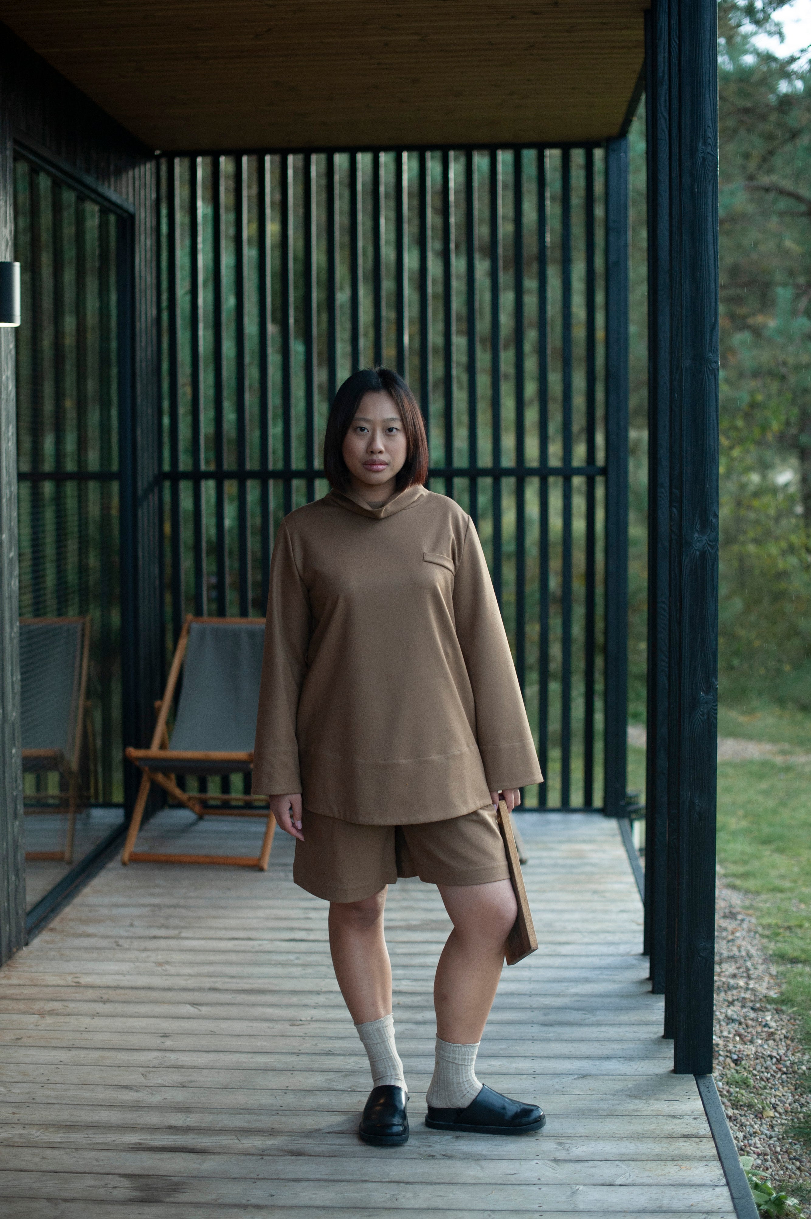 A monochrome ensemble of a relaxed fit high-neck top and classic Bermuda shorts in camel color wool.
