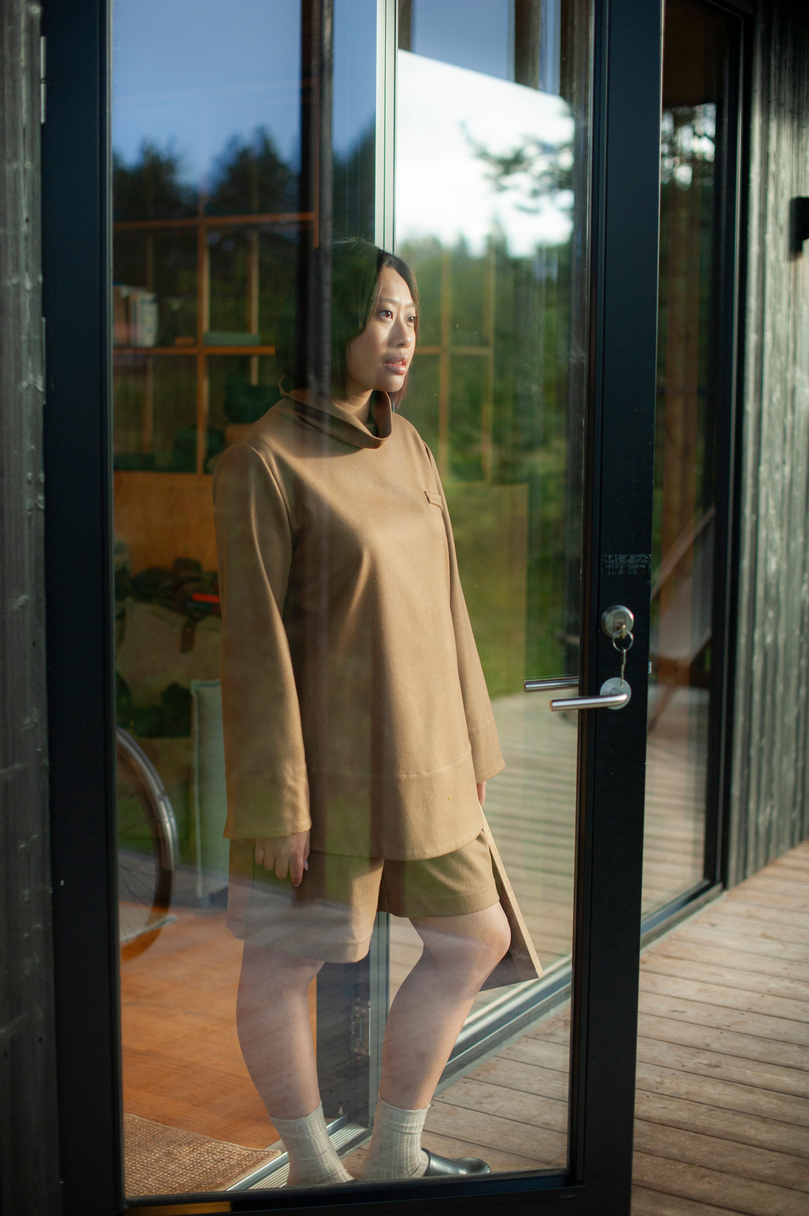 Minimalist camel color wool top with a relaxed roll neck, paired with a pair of matching pleated wool shorts.