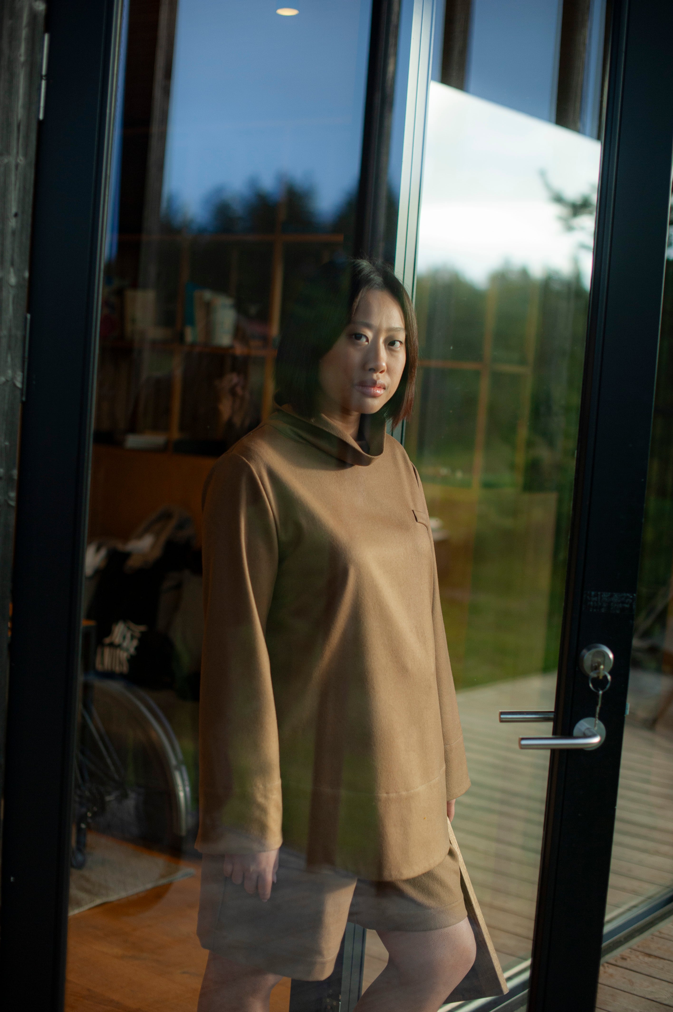 Minimalist camel color wool top with a relaxed roll neck, paired with a pair of matching pleated wool shorts.