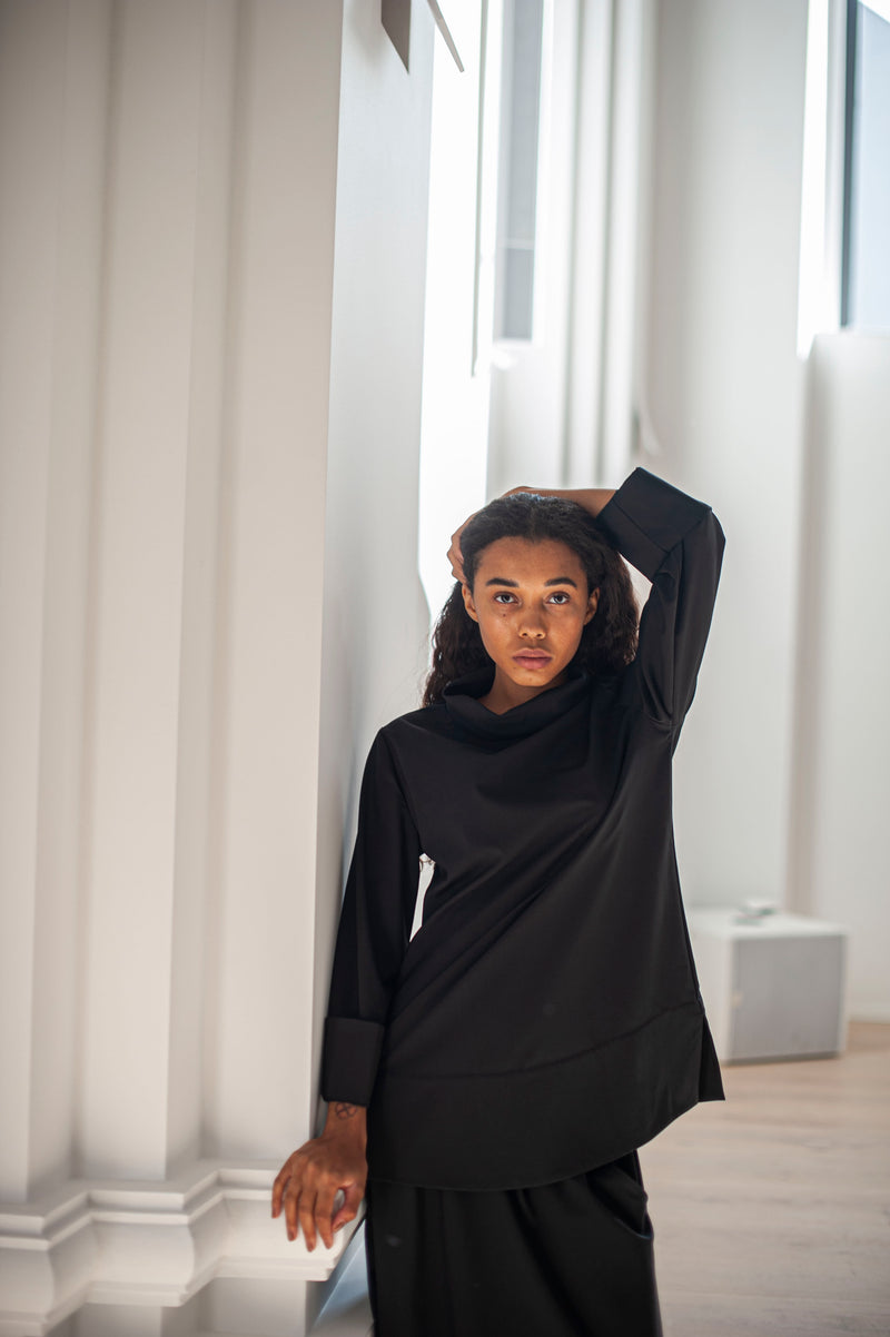 Black wool top with a broad hem, side slits,  and a high-neck. An elegant addition to your minimalist yet stylish wardrobe.