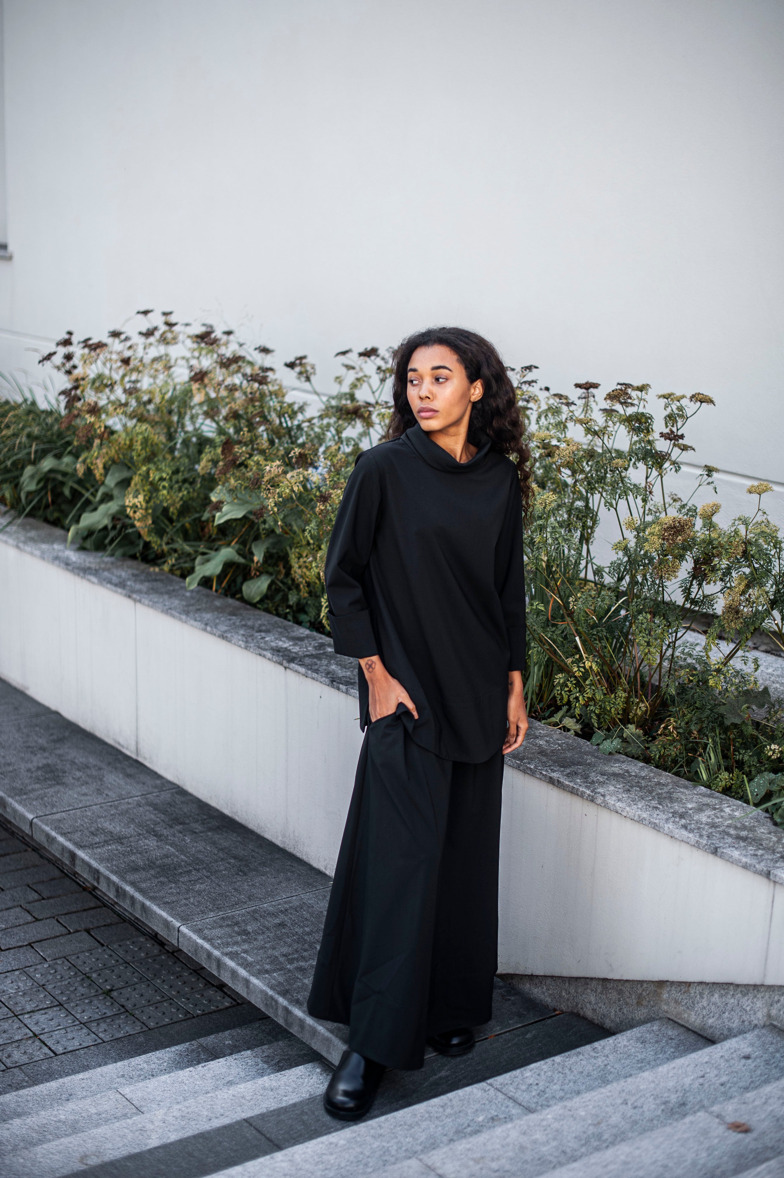 An outfit of a black relaxed wool top and a matching ankle-length skirt.