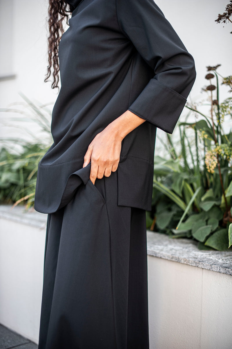 Women's black blouse with side slits and foldback sleeve cuffs. Made of 100% Merino wool.