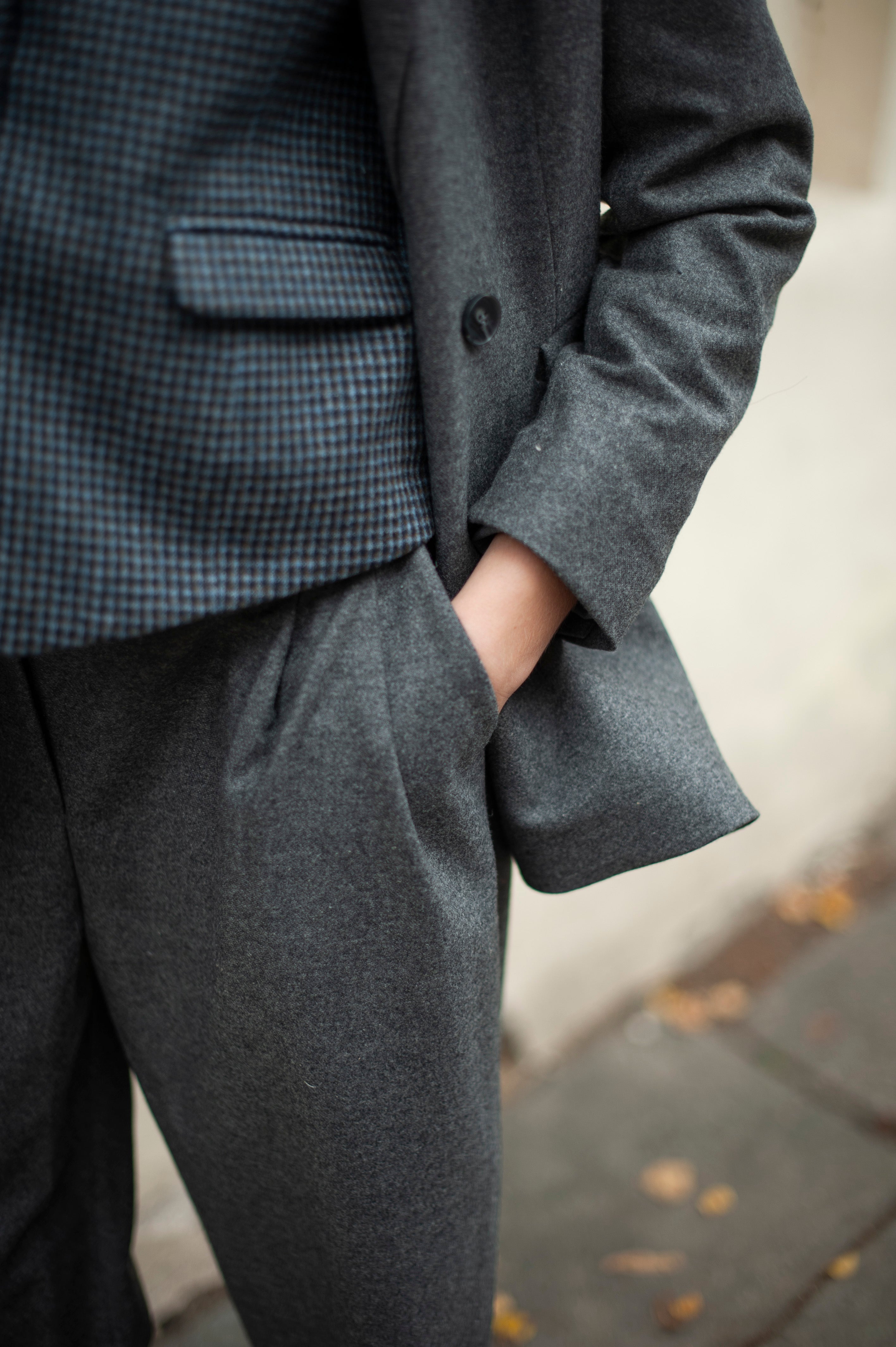 Women's tweed wool outfit of a grey double-breasted blazer, blue checks suit vest, and tapered barrel-leg pants with spacious pockets.