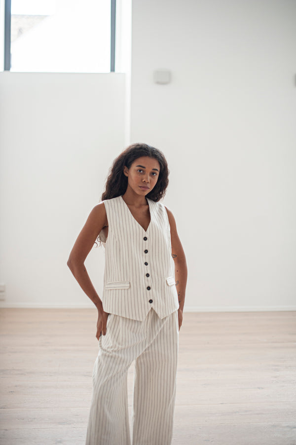 White pinstripe pleated pants and a matching button-up waistcoat