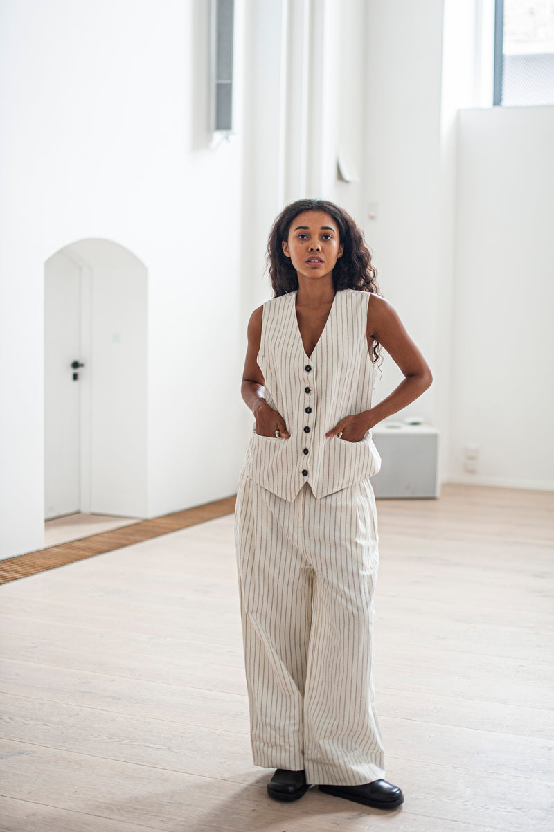 White striped wide-leg pleated pants and a classic waistcoat with a button closure