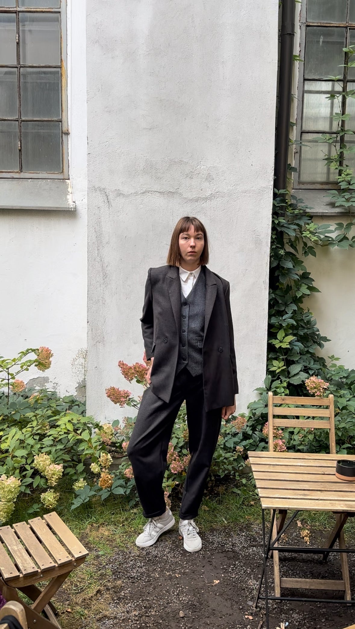 Women's pants suit including a double-breasted blazer with peak lapels, a suit vest, and pleated tapered-leg trousers.