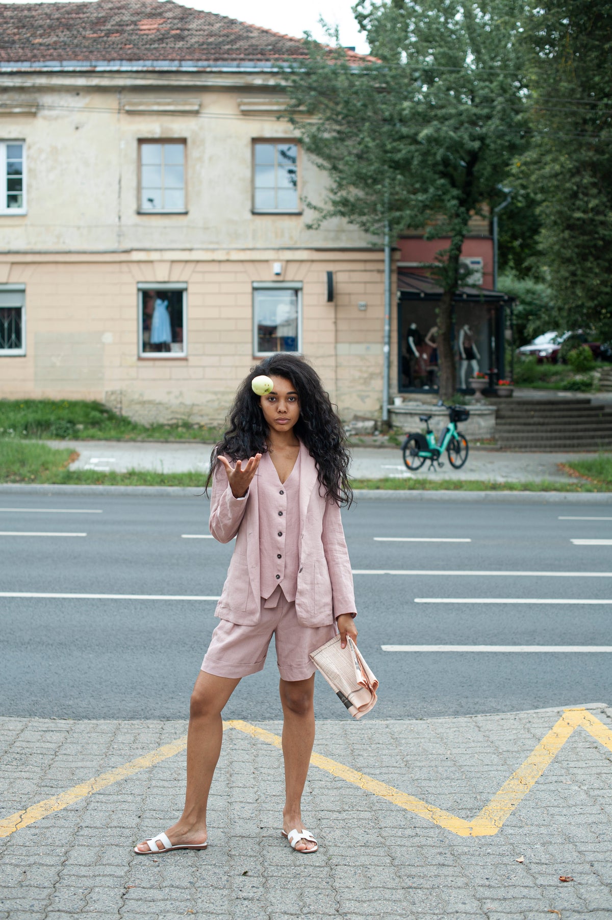 Woman wearing a dusty pink linen blazer set with oversized shorts on a city street