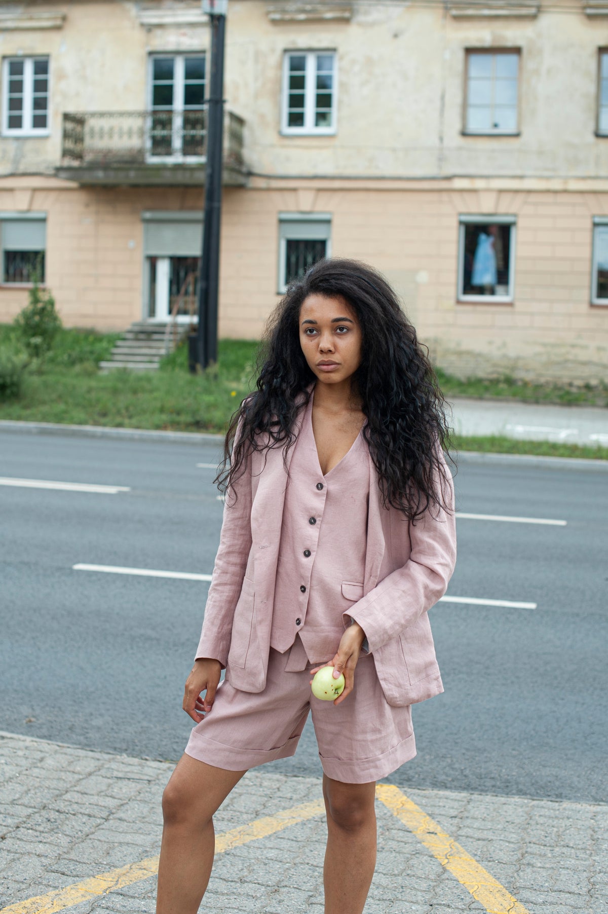 Close-up of a dusty pink linen blazer featuring large patch pockets and horn buttons.
