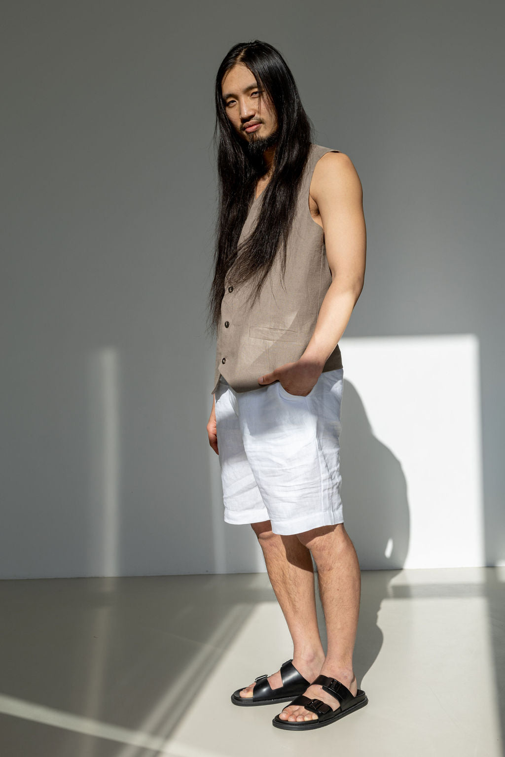 White linen shirts boasting a drawstring paired with a beige linen waistcoat. Men's summer outfit.