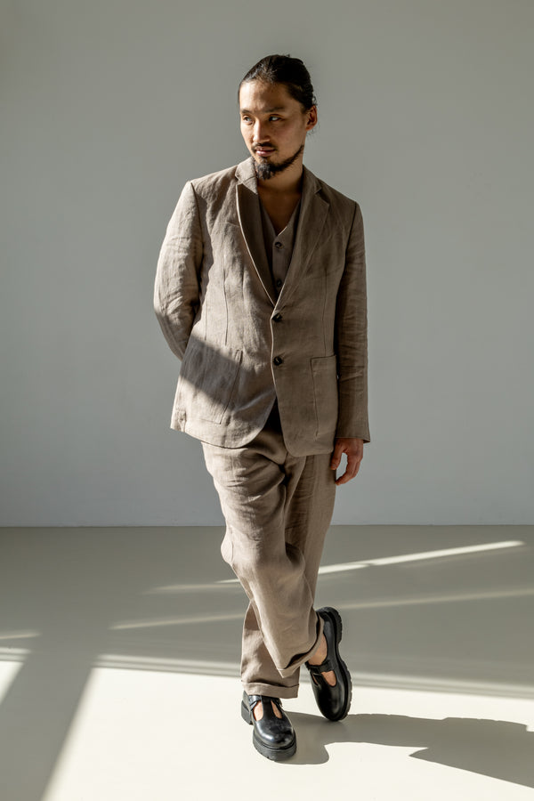 Beige linen three-piece linen suit of a classic blazer, waistcoat, and wide pants