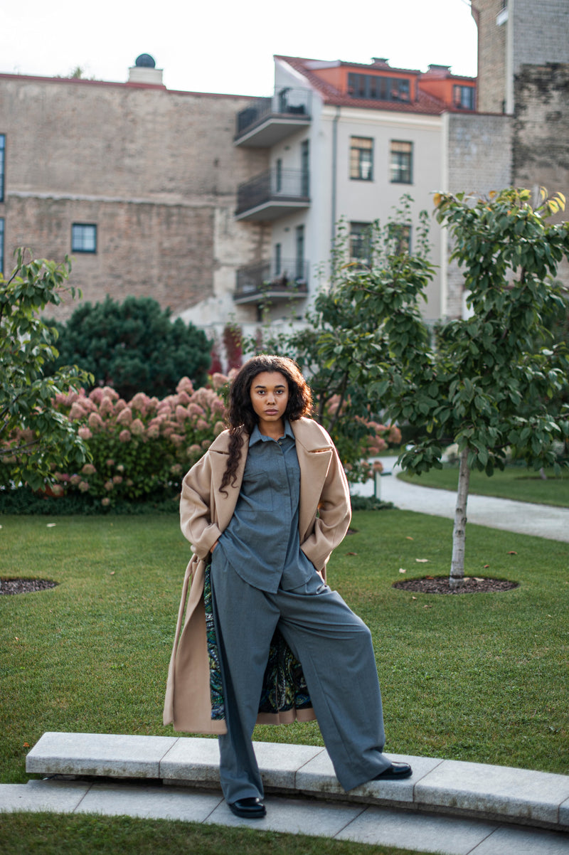 An outfit of a Merino wool collar shirt, matching pleated pants, and a camel coat