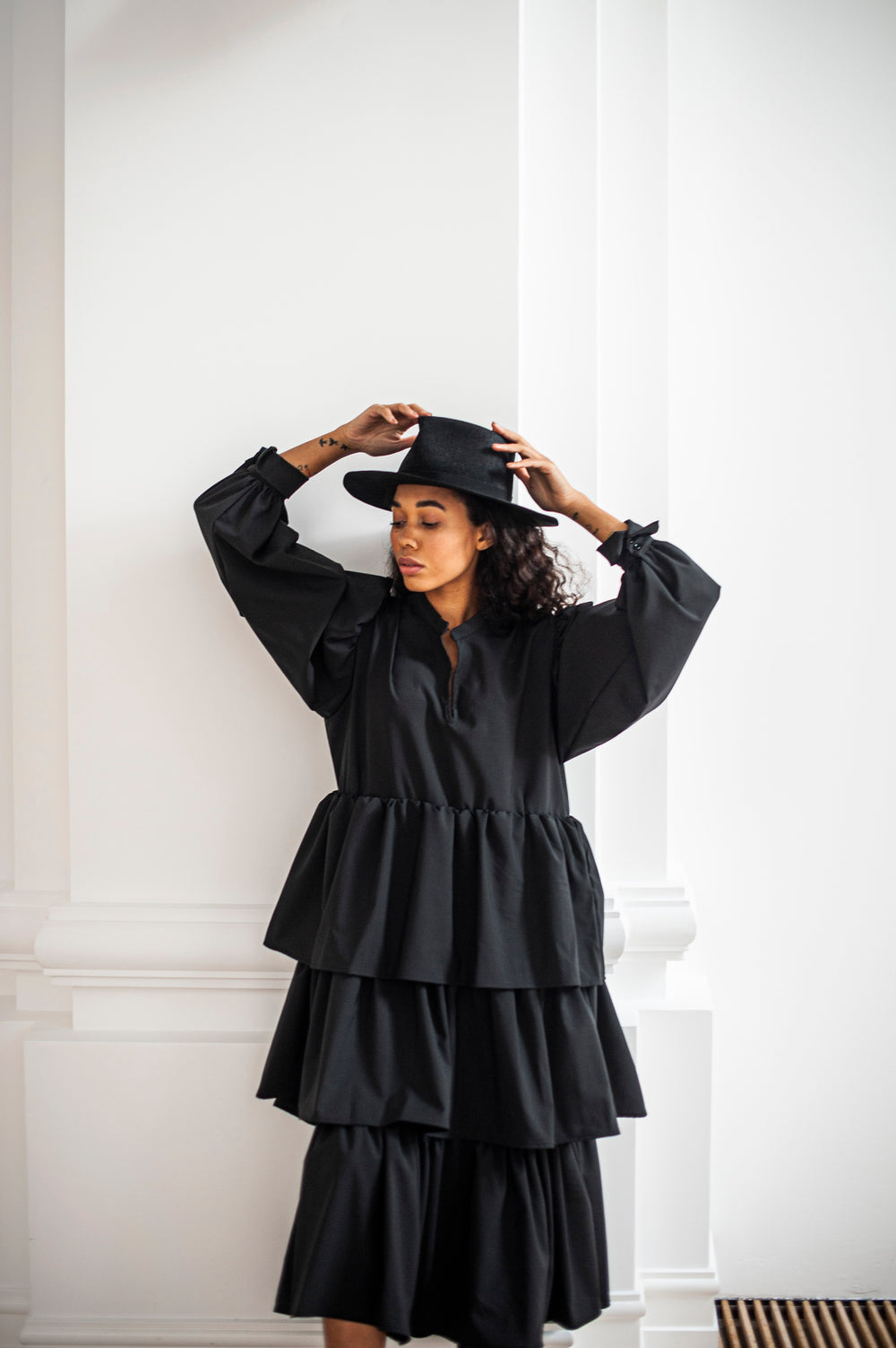 Black merino wool dress with a ruffle skirt and voluminous sleeves boasting French cuffs.