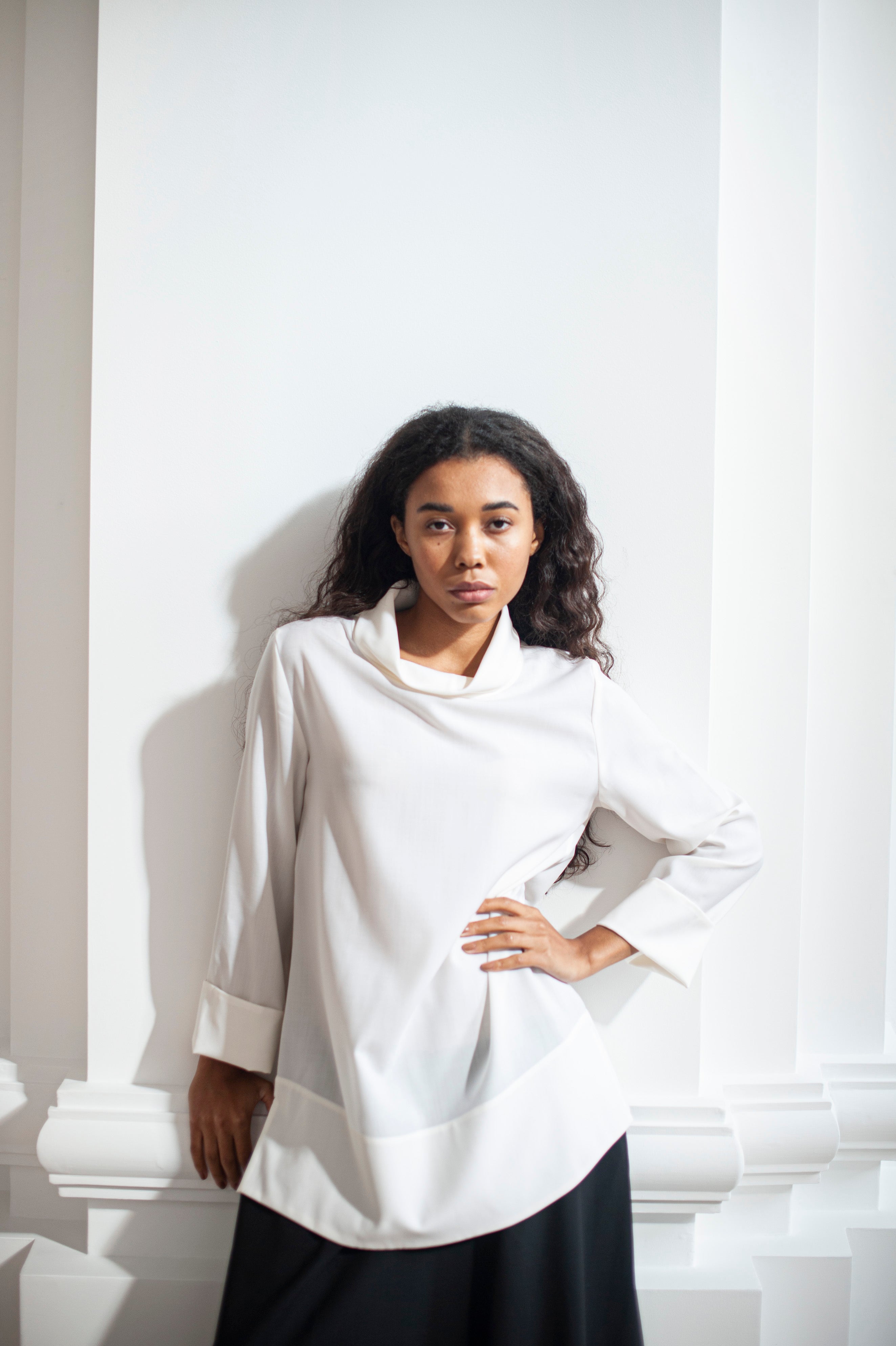 Minimalist white blouse with side slits. Crafted from 100% Merino wool.