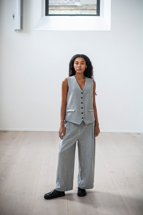 Grey heavy cotton pleated pants with a zipper closure and a classic button-up vest. Perfect summer go-to for work and every day.