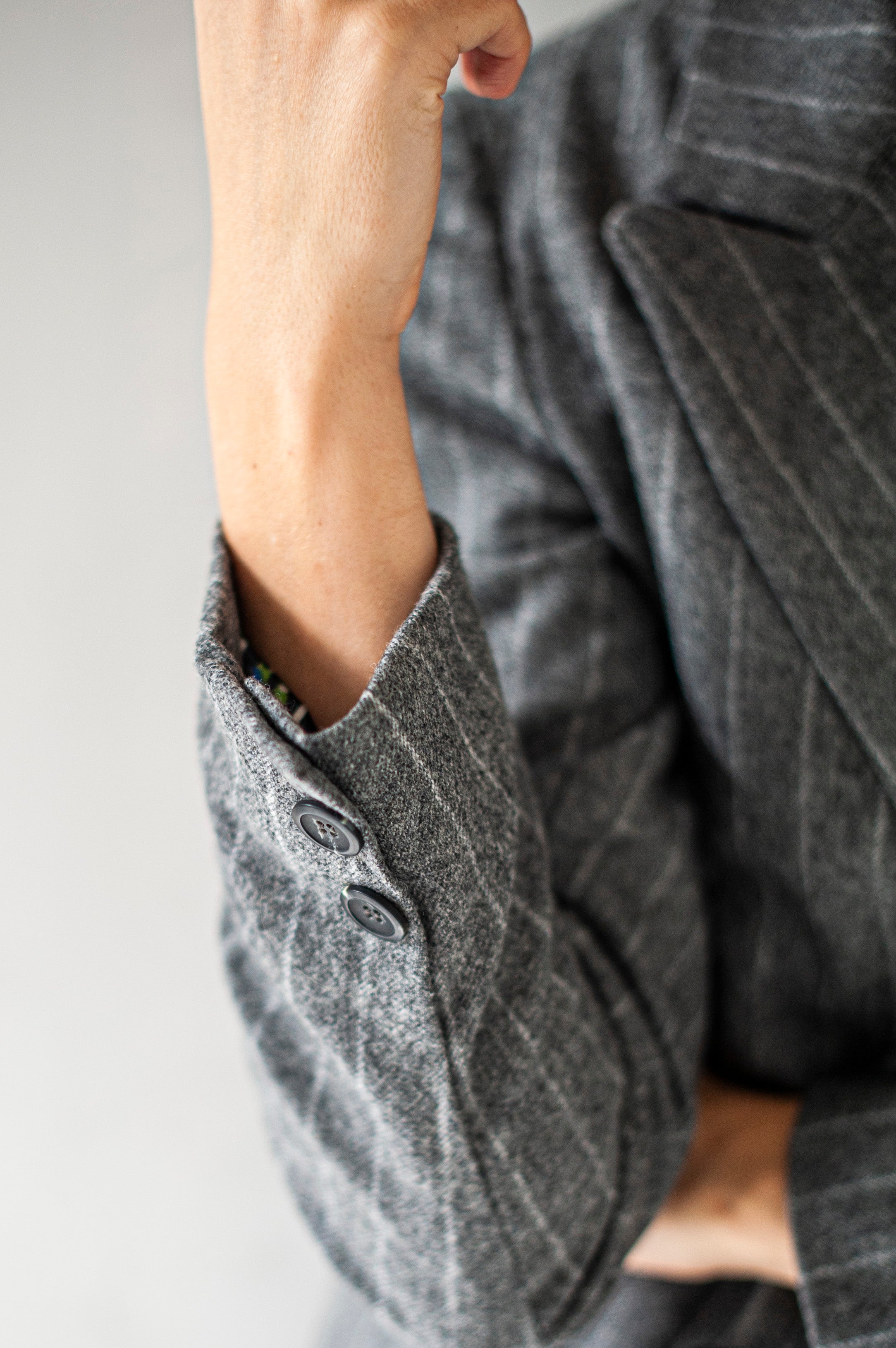 A buttoned cuff of a striped tweed blazer.