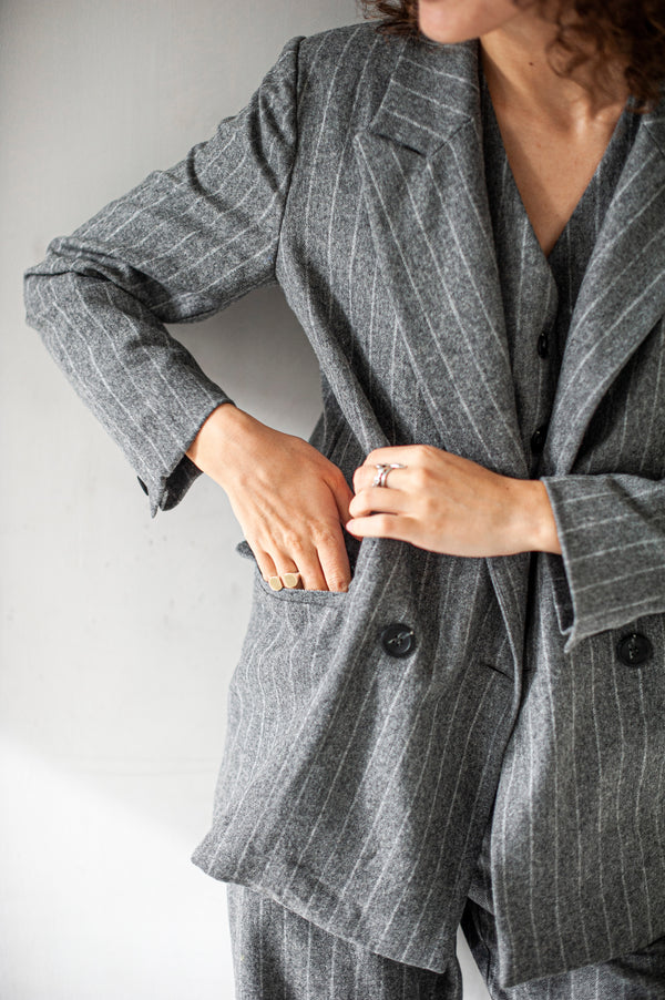Grey striped wool blazer with a double-breasted closure and front pockets.