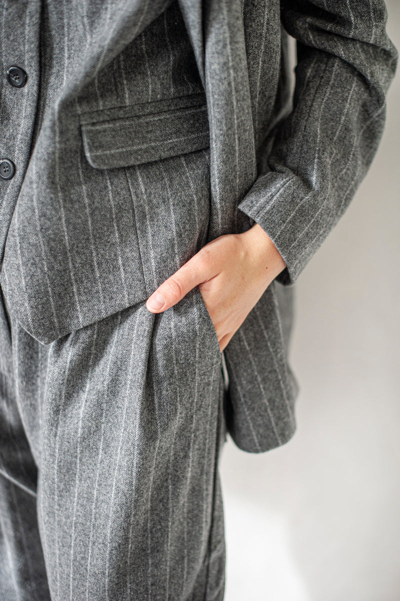 Three-piece suit made of 100% wool. The suit includes a double-breasted blazer, a waist coat, and a pair of 0-shaped trousers