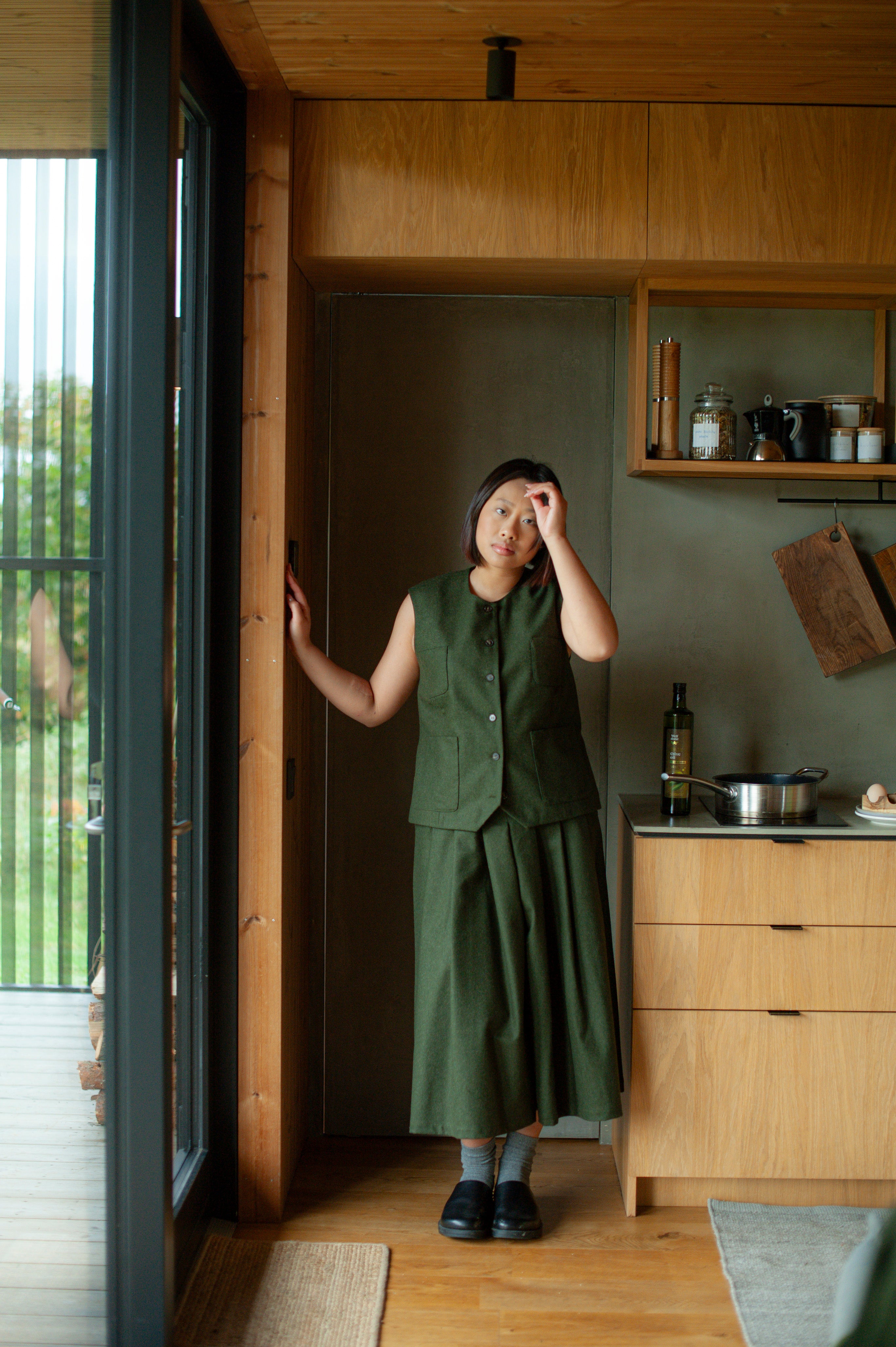 Green set of a wool button-up vest and pleated calf-length culottes.