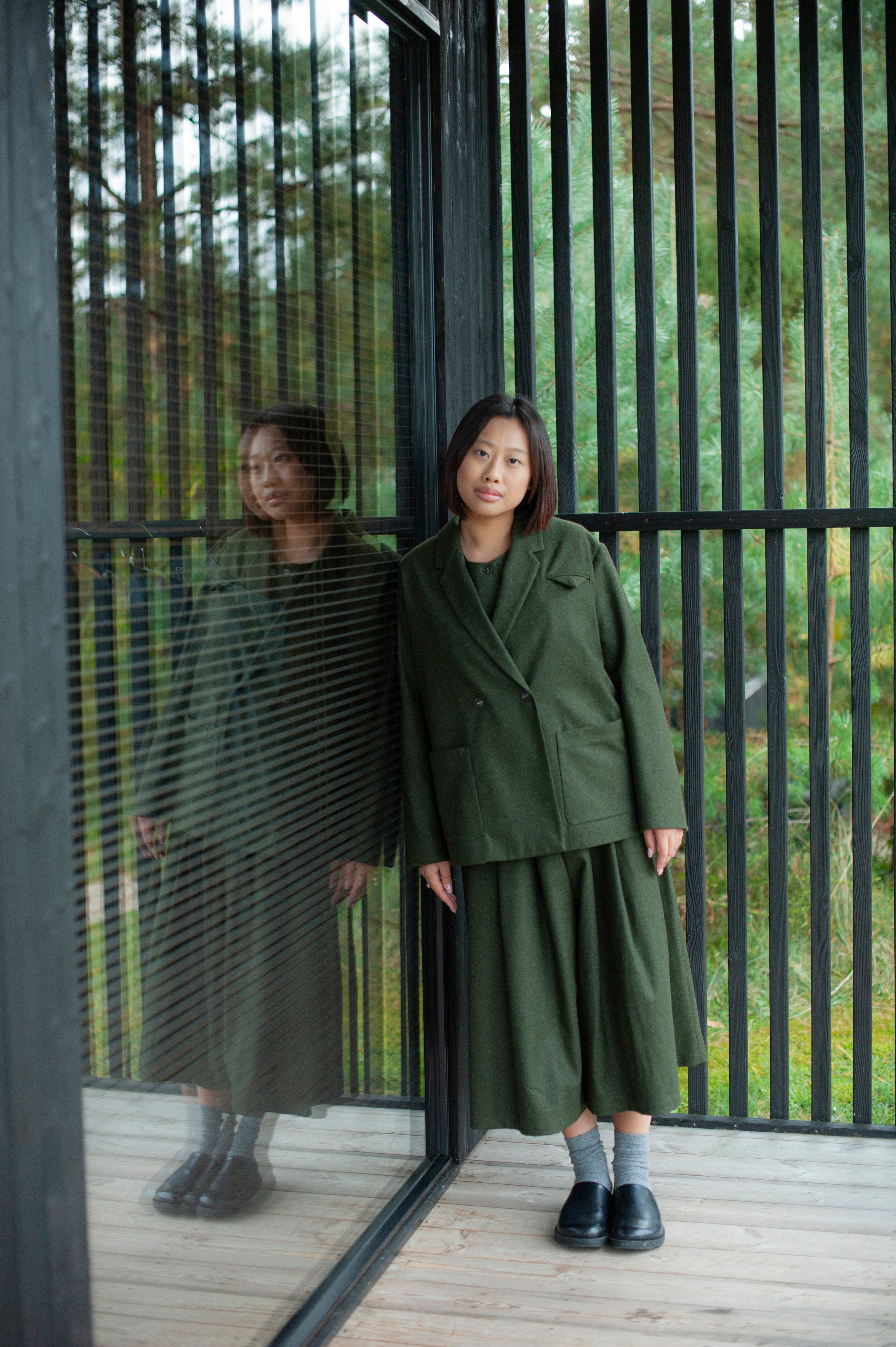 Boxy-fit green wool-blend blazer with a double-breasted closure, large patch pockets, and a decorative pocket square detail. The blazer is paired with coordinating culottes featuring a pleated waistband.