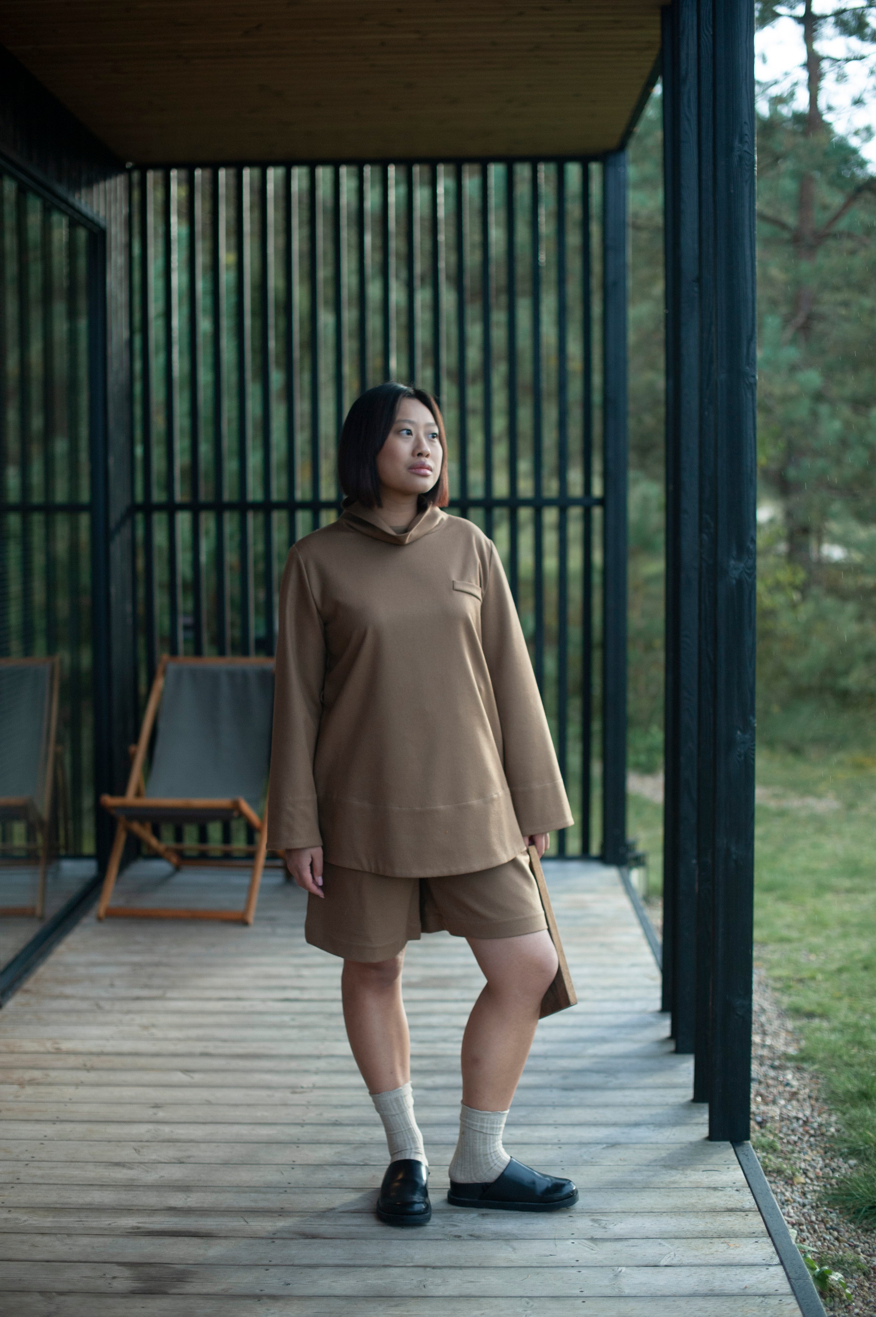 A monochrome ensemble of a relaxed fit high-neck top and classic Bermuda shorts in camel color wool. 