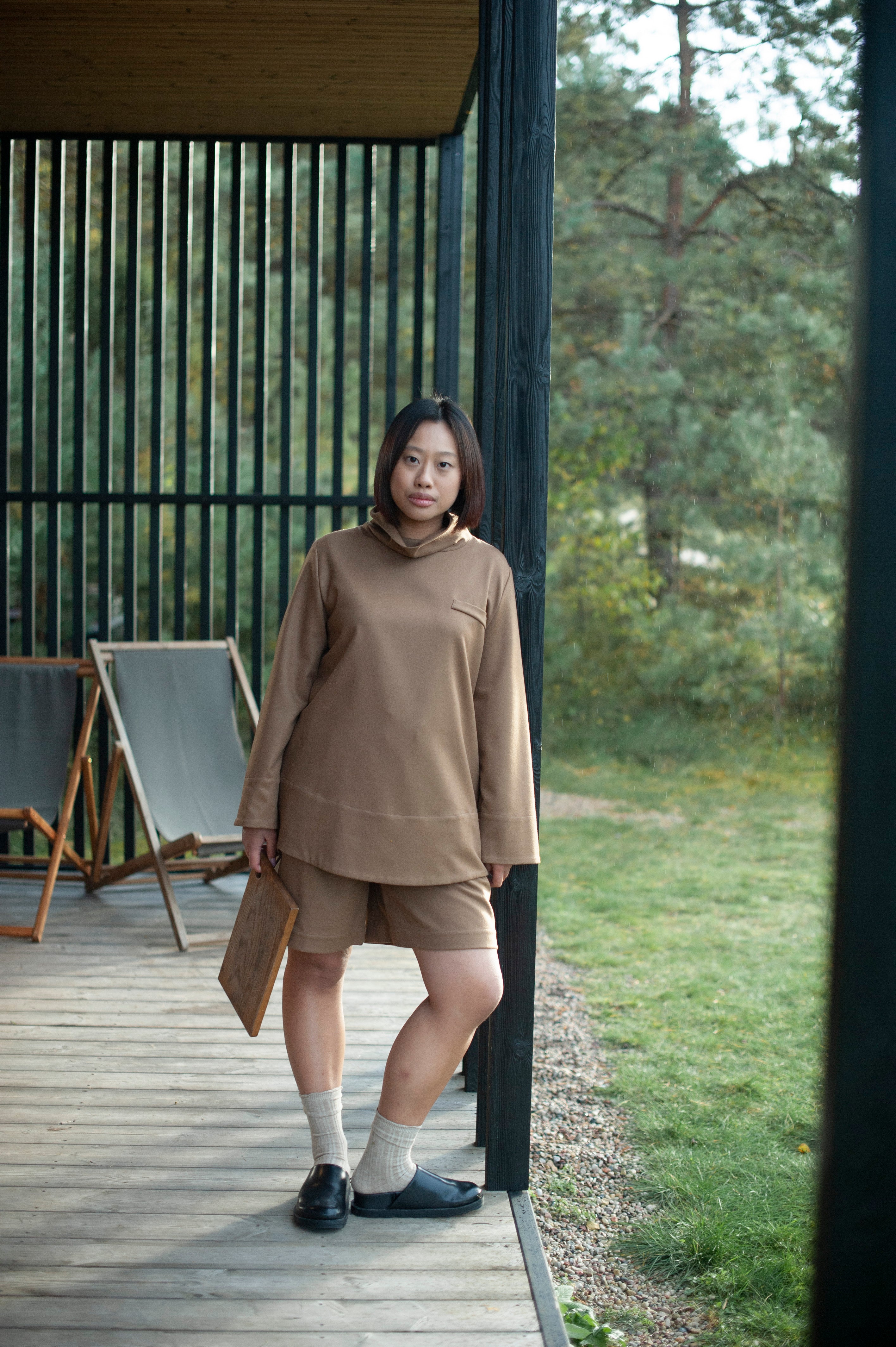 A monochrome ensemble of a relaxed fit high-neck top and classic Bermuda shorts in camel color wool. 