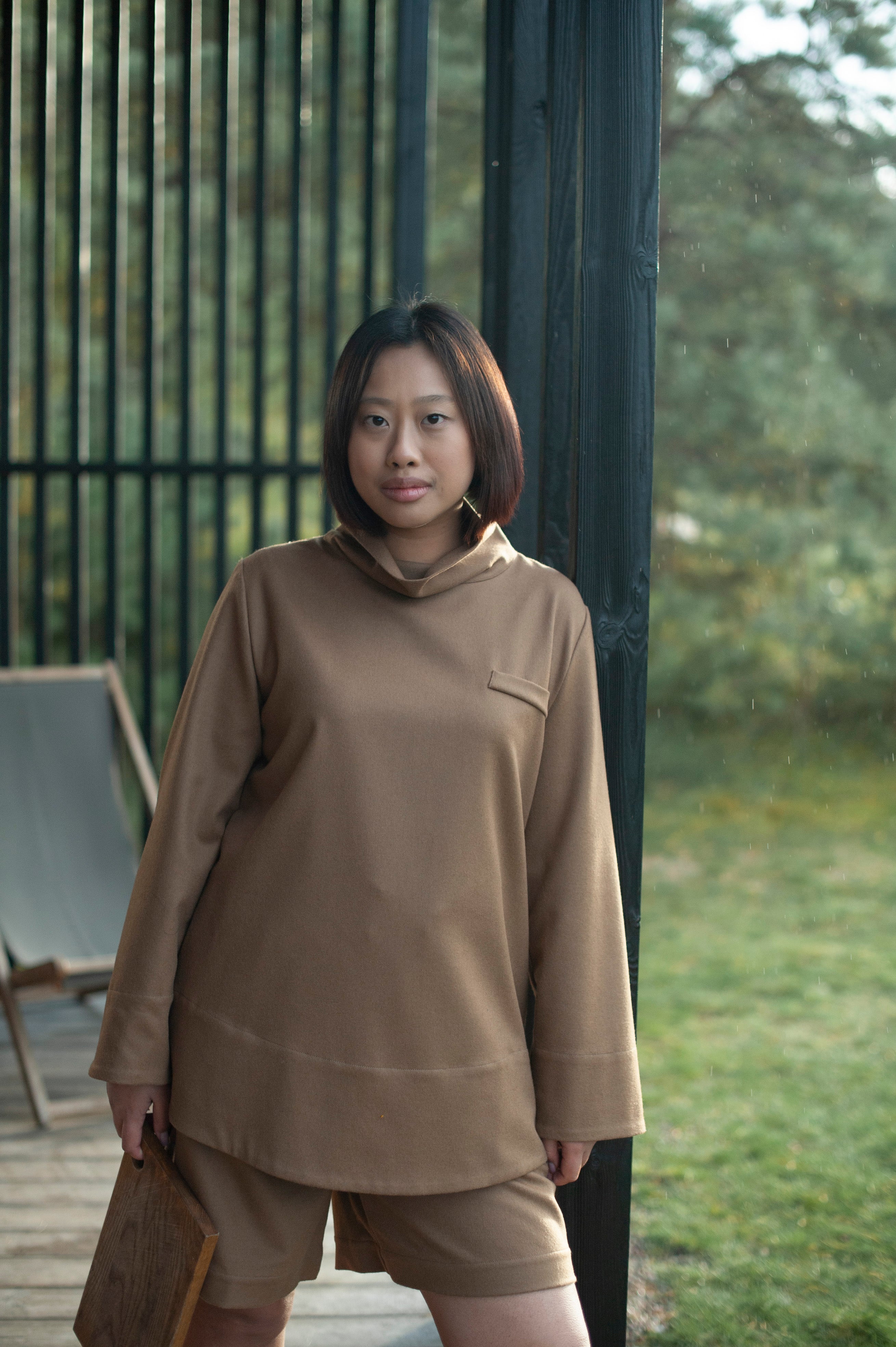 Camel color wool top with a high neck and a decorative detail imitating a chest pocket.